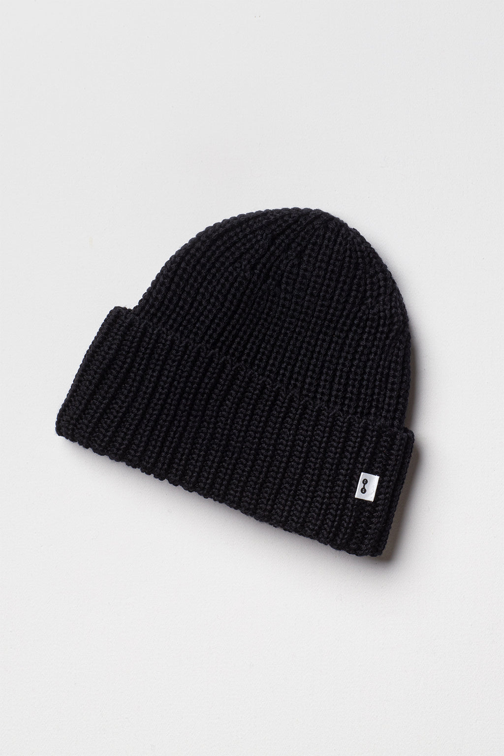 Bonnet homme et femme noir en laine mérinos à revers, packshot sur fond clair montrant la maille côtelée. Made in France.