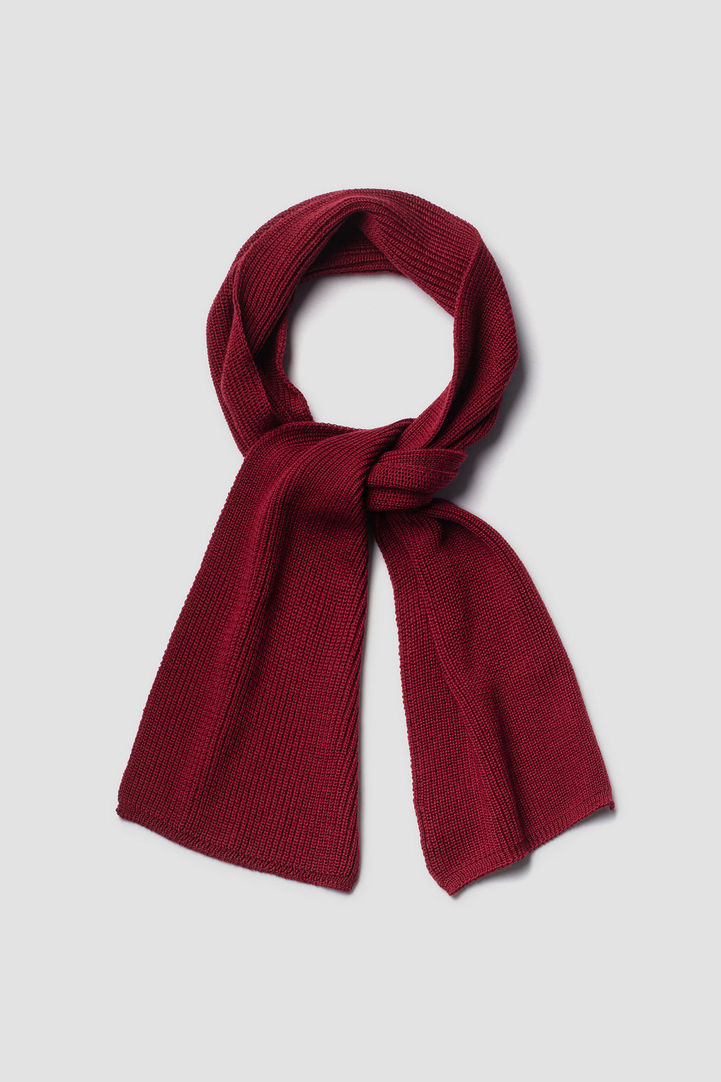 Écharpe rouge rubis en laine mérinos, présentée nouée sur fond clair.