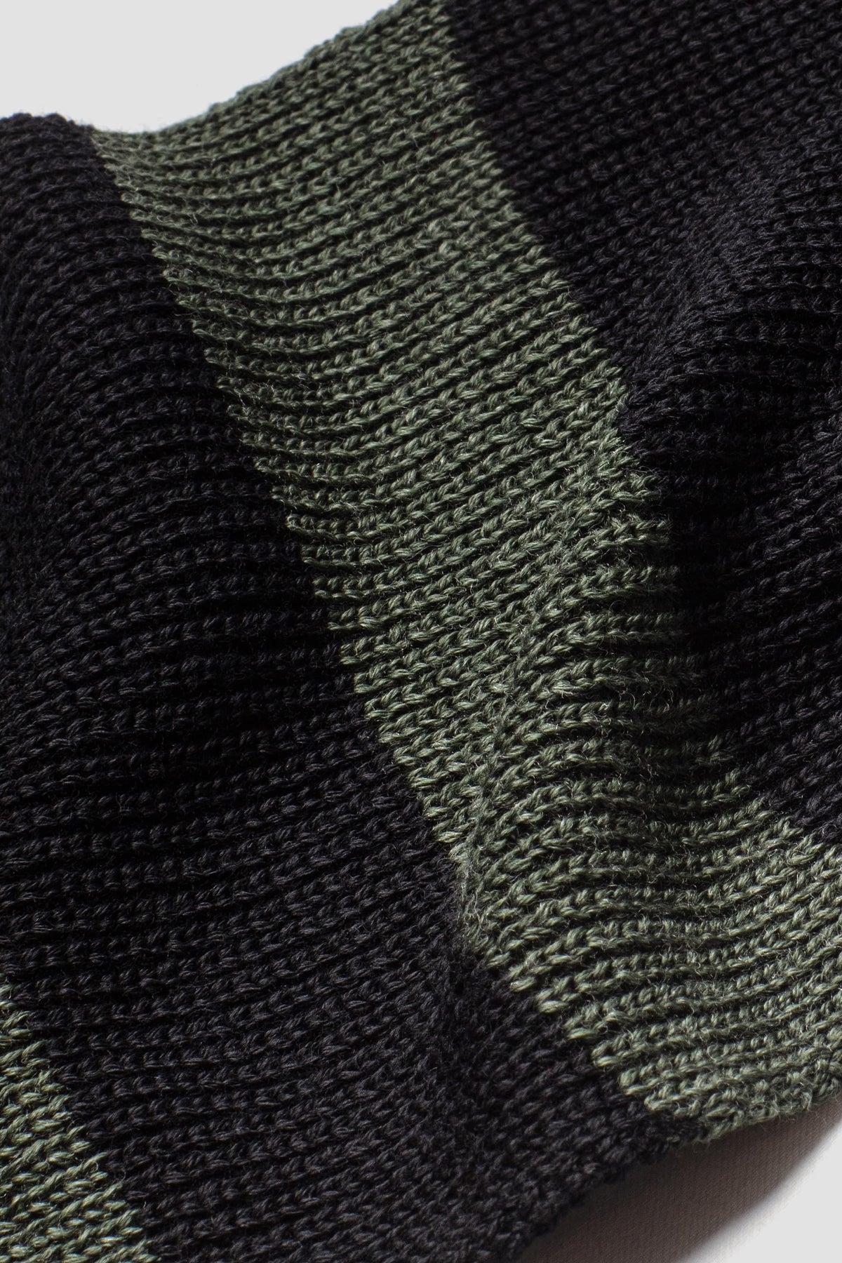 Écharpe rayée vert kaki et noir en laine mérinos, gros plan sur la maille et la jonction des couleurs.