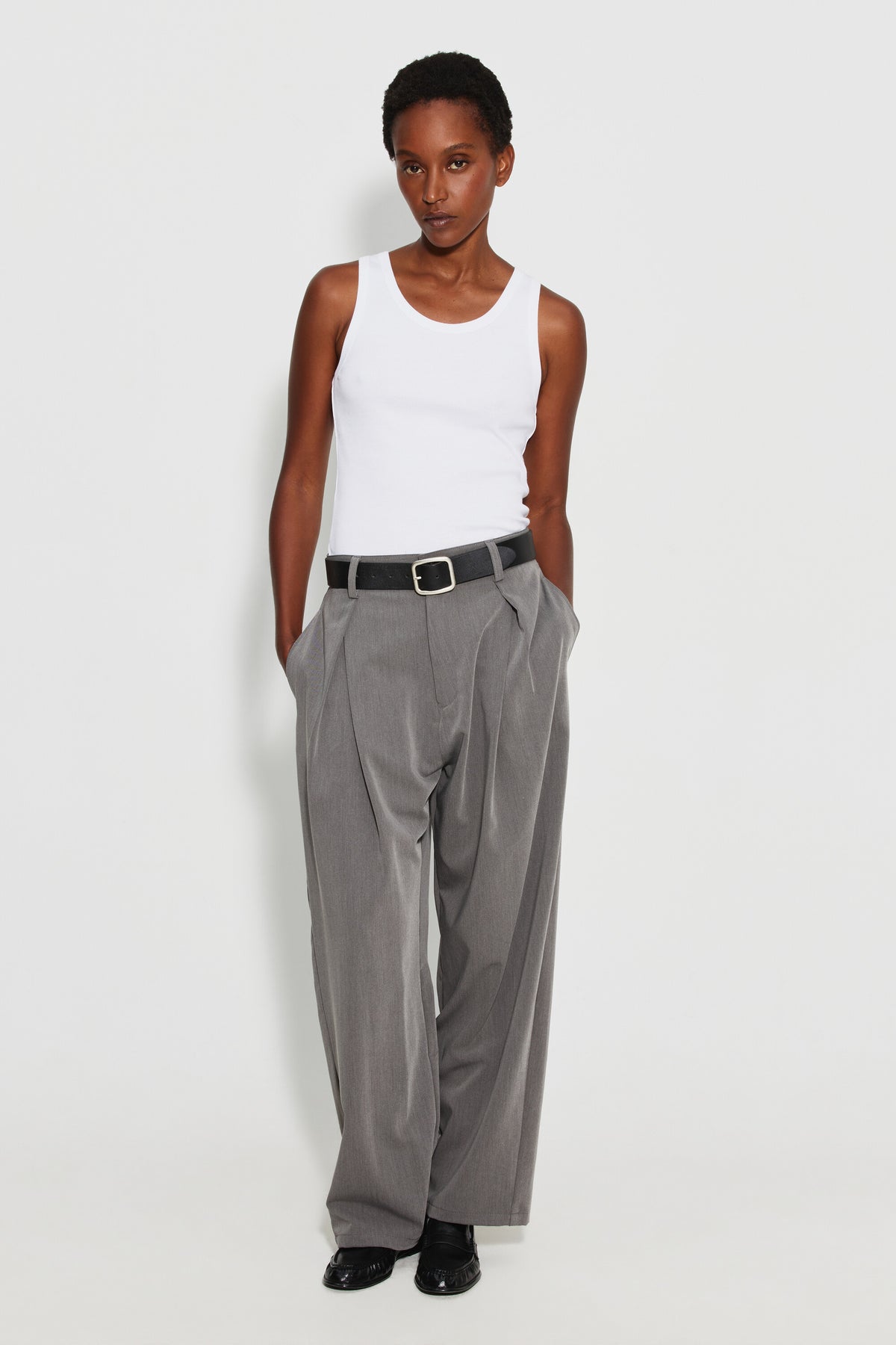 Débardeur Marcel Signature blanc femme, porté avec un pantalon large gris et une ceinture noire, vue de face en pied.