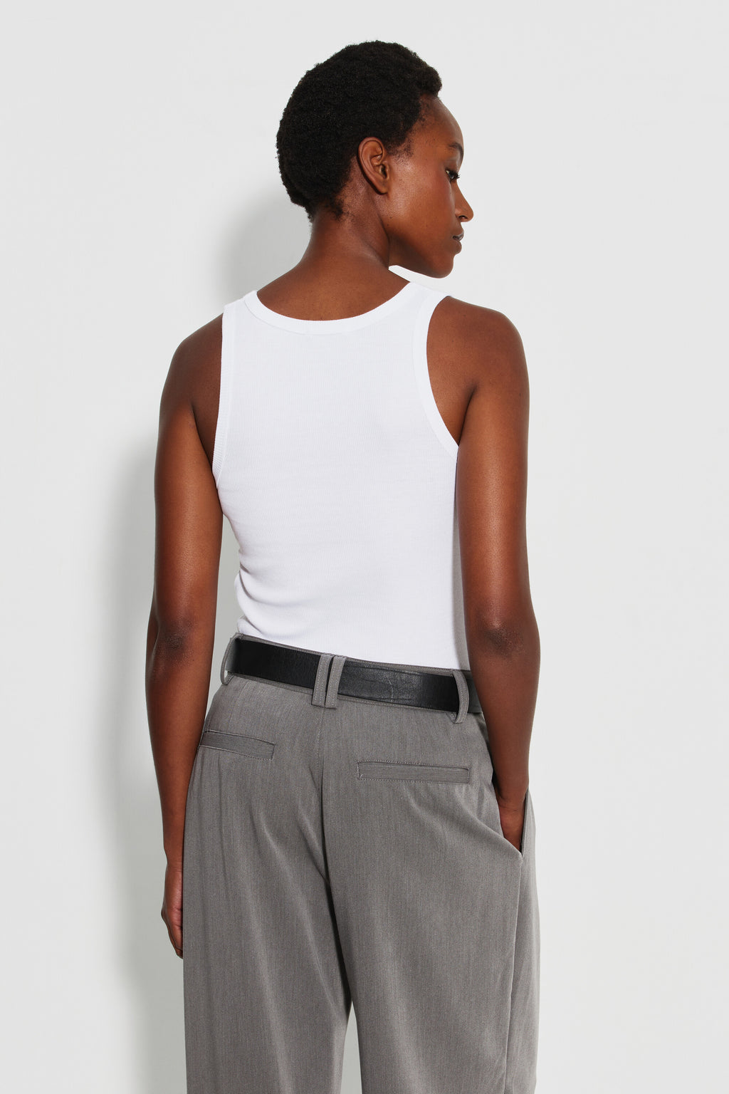 Débardeur Marcel Signature blanc femme en coton Pima côtelé, porté de dos avec un pantalon gris et une ceinture noire.