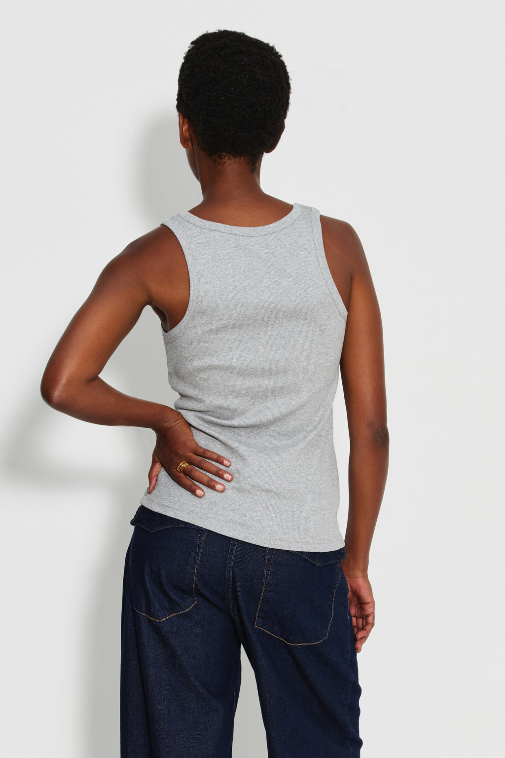 Débardeur Marcel Signature gris chiné femme en coton Pima côtelé, porté de dos avec un jean bleu foncé, une main posée sur la hanche.