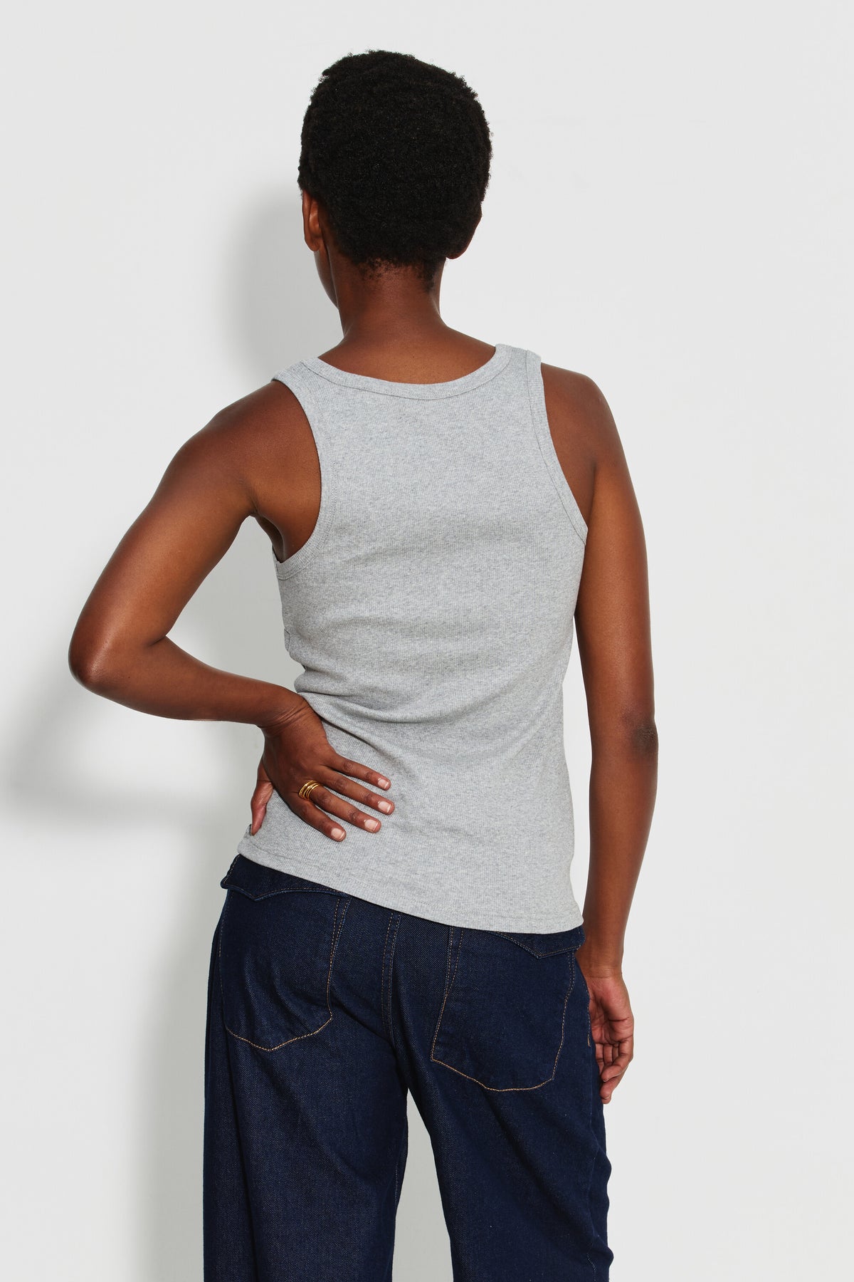 Débardeur Marcel Signature gris chiné femme en coton Pima côtelé, porté de dos avec un jean bleu foncé, une main posée sur la hanche.