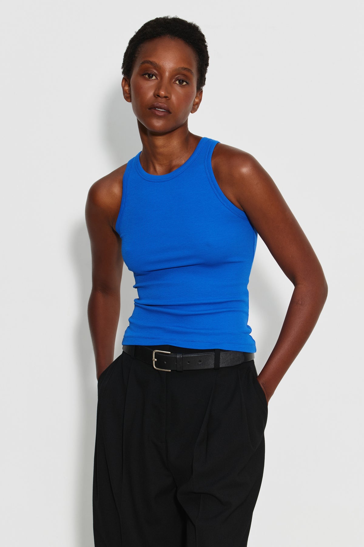 Débardeur Top Marcel bleu femme en coton Pima et élasthanne, porté de face avec un pantalon noir, les mains dans les poches.