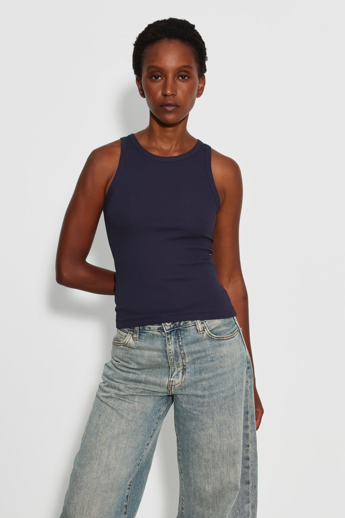 Débardeur Top Marcel bleu marine femme, porté de face avec un jean bleu clair, une main derrière le dos.
