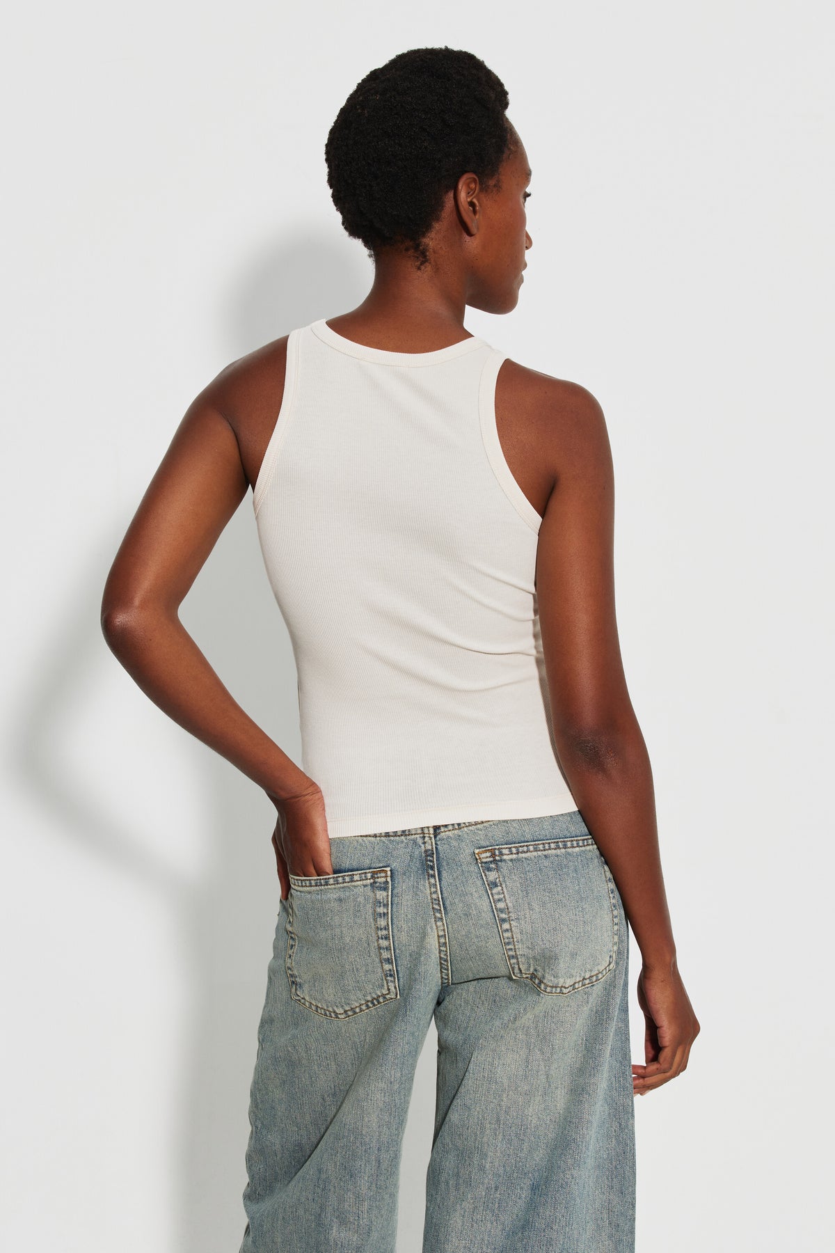 Débardeur Top Marcel écru femme en coton Pima et élasthanne, porté de dos avec un jean bleu clair, une main dans la poche.