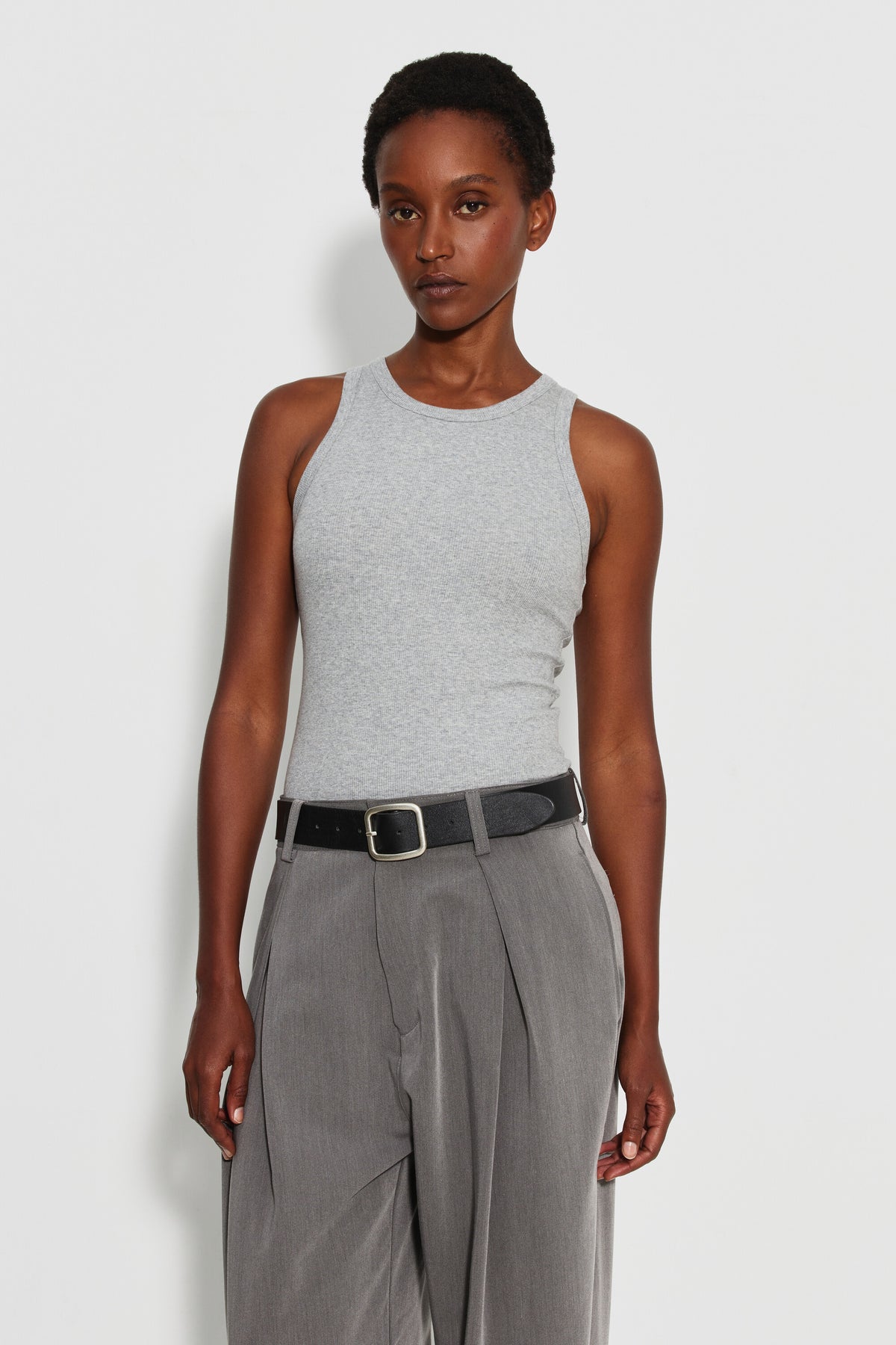 Débardeur Top Marcel gris femme, porté de face et rentré dans un pantalon gris à ceinture noire, cadrage à mi-cuisse.