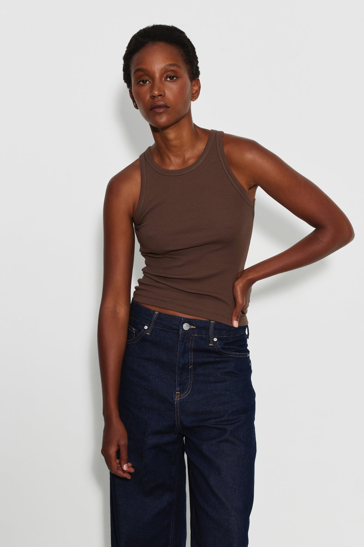 Débardeur Top Marcel marron femme en coton Pima et élasthanne, porté de face avec un jean bleu foncé, une main sur la hanche.