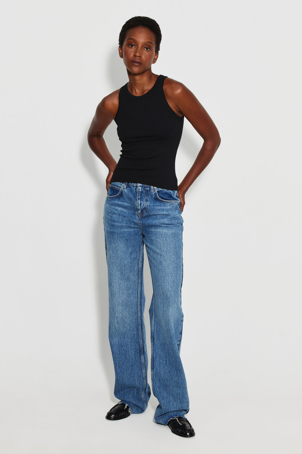 Débardeur Top Marcel noir femme, porté avec un jean large bleu et des chaussures noires, vue de face en pied.
