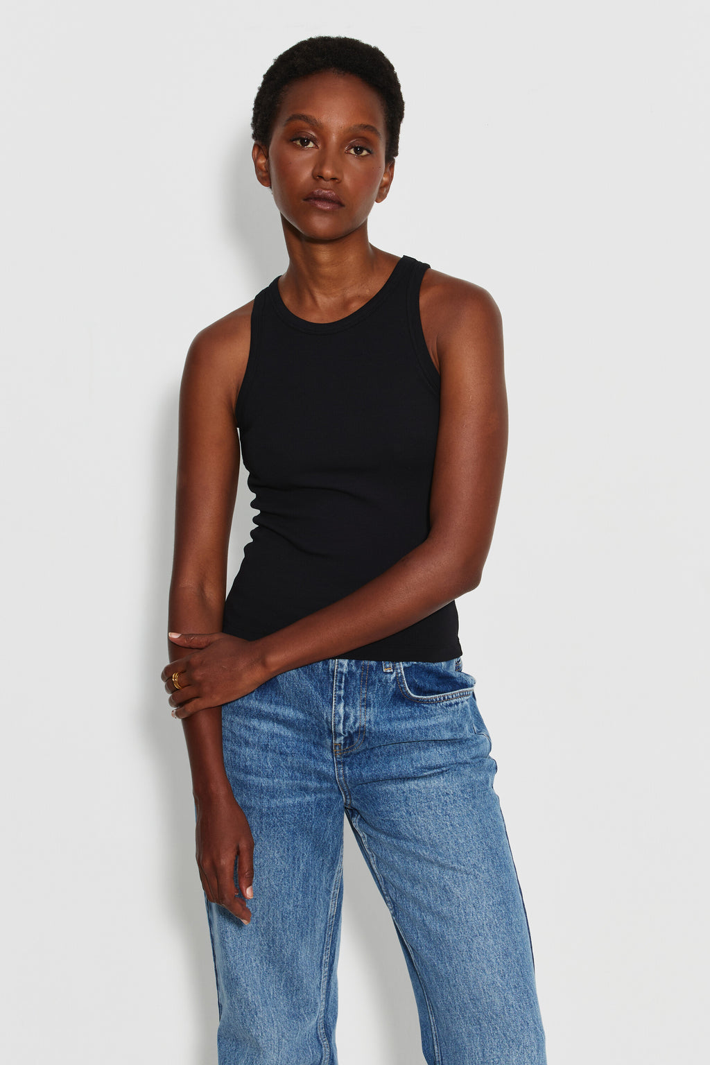 Débardeur Top Marcel noir femme en coton Pima et élasthanne, porté de face avec un jean bleu, les mains croisées devant le corps.