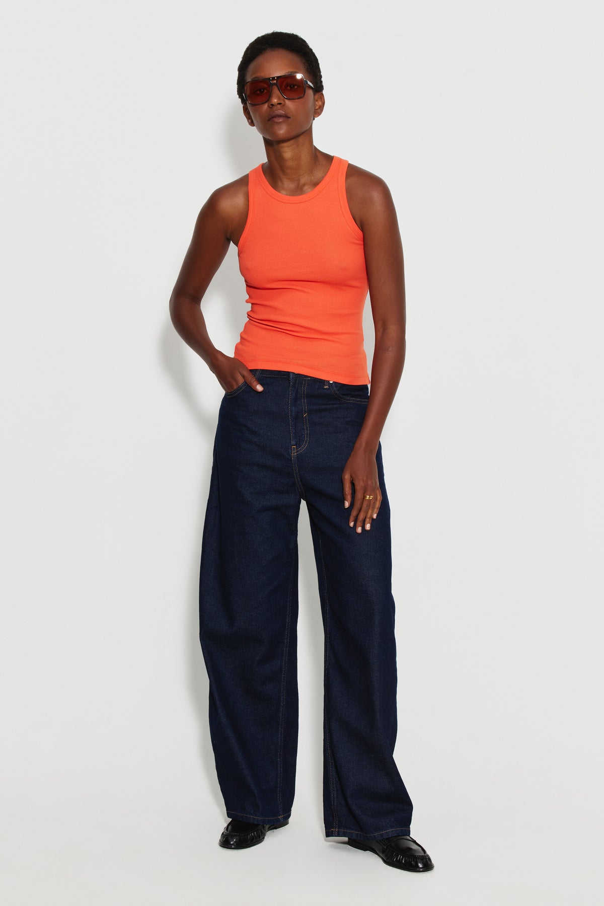 Débardeur Top Marcel orange femme, porté avec un jean large bleu foncé et des lunettes de soleil, vue de face en pied.