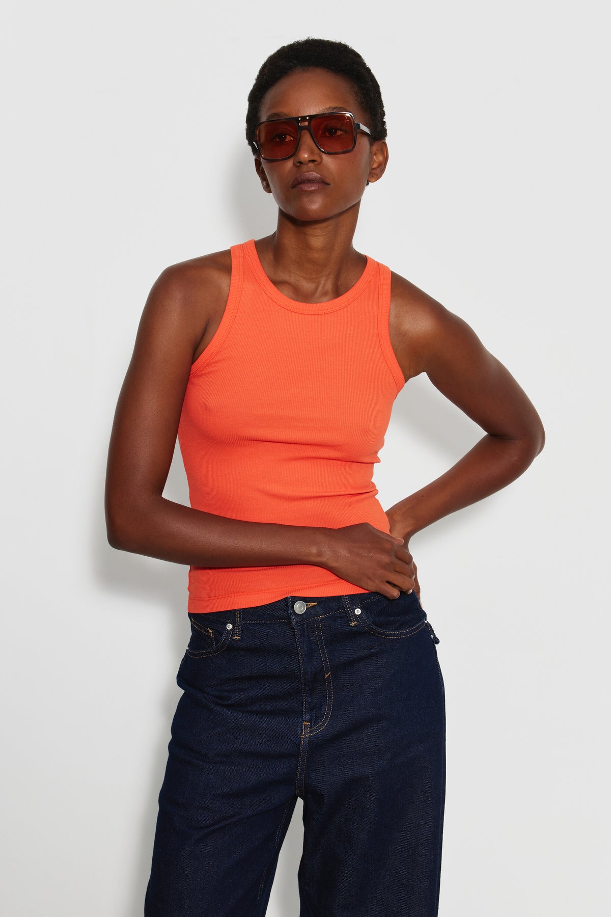 Débardeur Top Marcel orange femme en coton Pima et élasthanne, porté de face avec un jean bleu foncé et des lunettes de soleil.