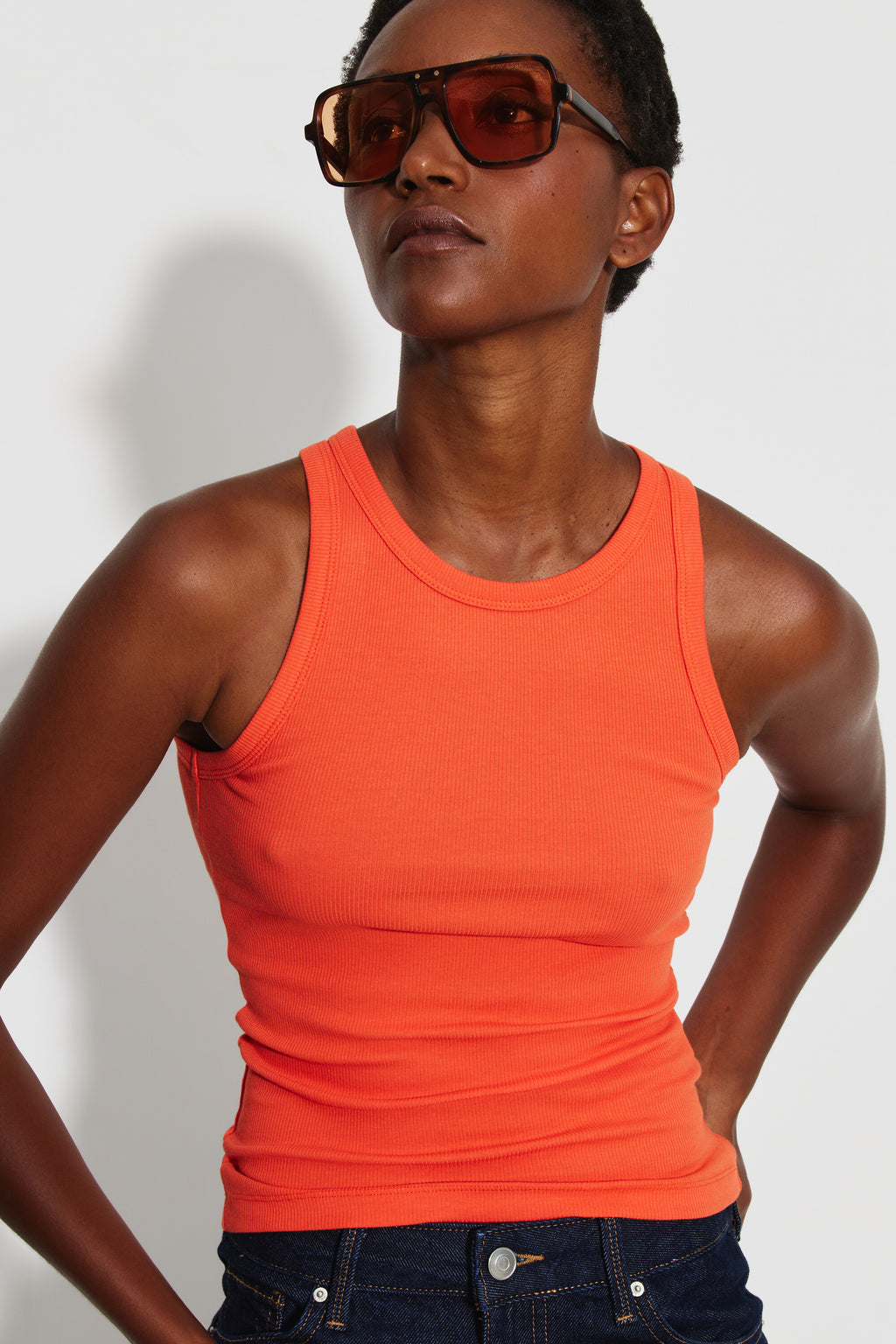 Débardeur Top Marcel orange femme, portrait rapproché avec des lunettes de soleil montrant l’encolure ronde et la coupe ajustée.