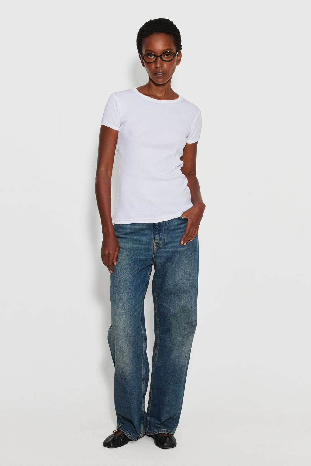 Maillot de corps femme blanc à manches courtes en coton Pima côtelé, porté avec un jean bleu et des chaussures noires, vue de face en pied.