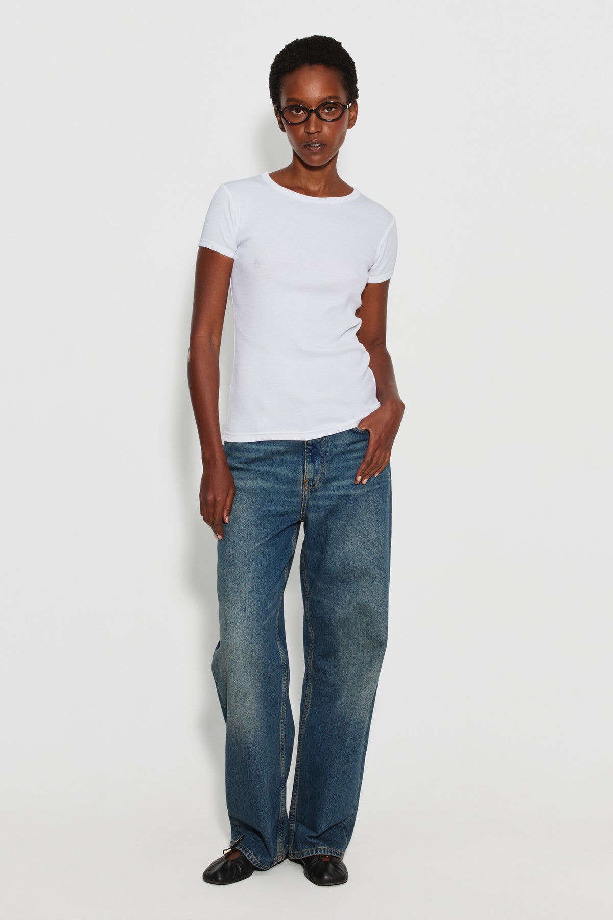 Maillot de corps femme blanc à manches courtes en coton Pima côtelé, porté avec un jean bleu et des chaussures noires, vue de face en pied.