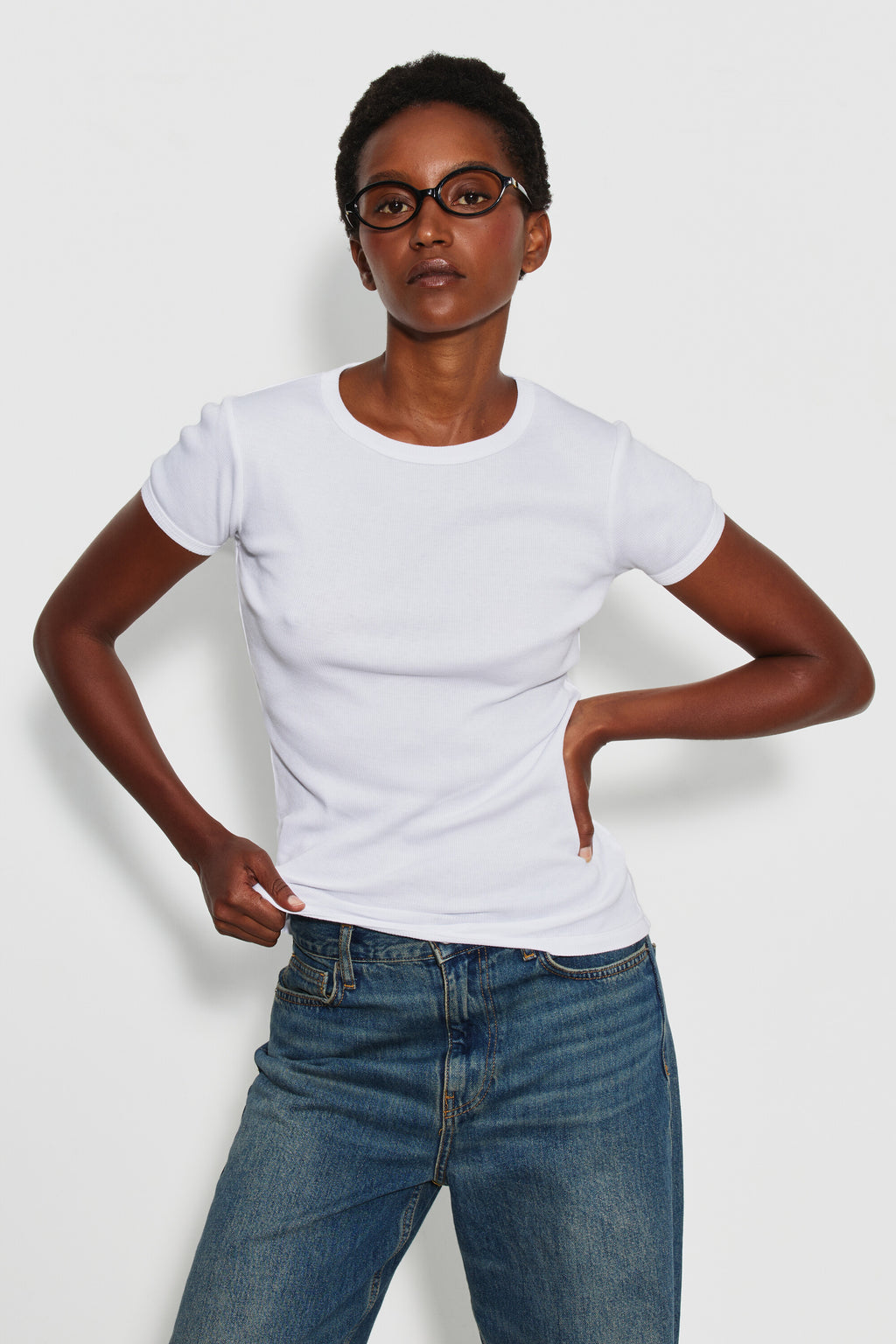 Maillot de corps femme blanc à manches courtes en coton Pima côtelé, porté de face avec un jean bleu, une main sur la hanche. Made in France.