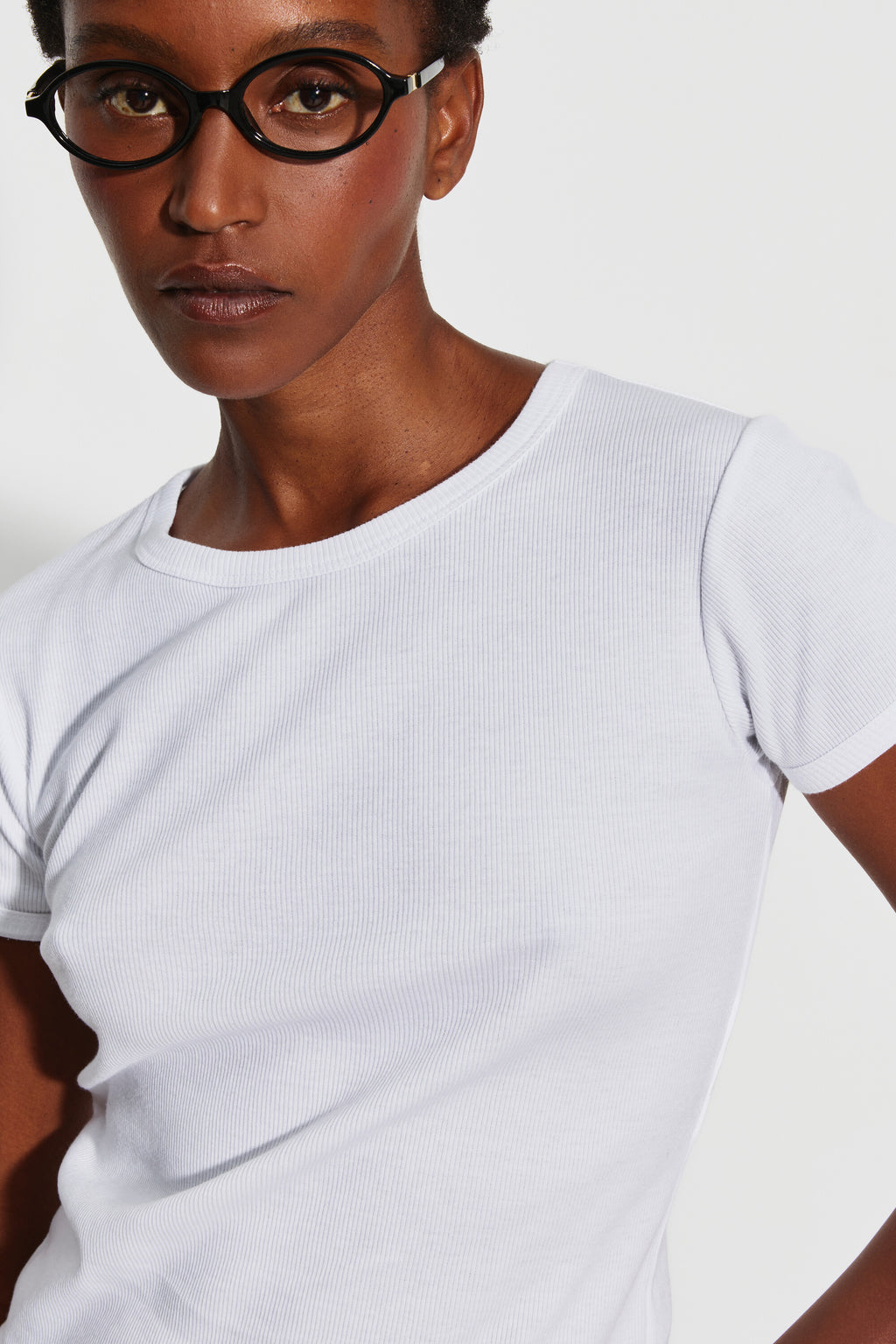 Maillot de corps femme blanc à manches courtes en coton Pima côtelé, vue rapprochée du col rond et des manches, mannequin portant des lunettes.