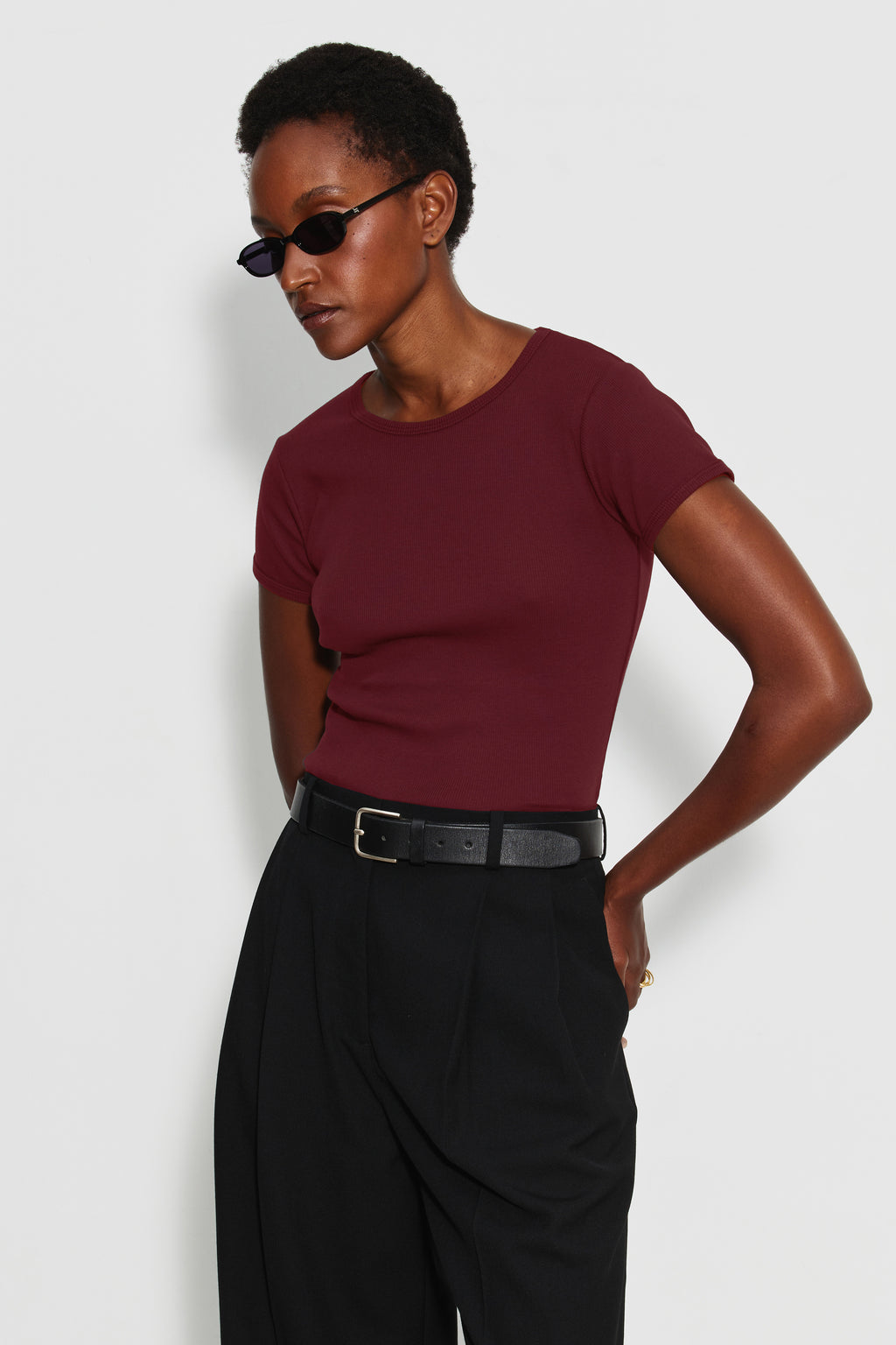 Maillot de corps femme bordeaux en coton pima côtelé à manches courtes, porté de trois quarts avec un pantalon noir ceinturé. Made in France.