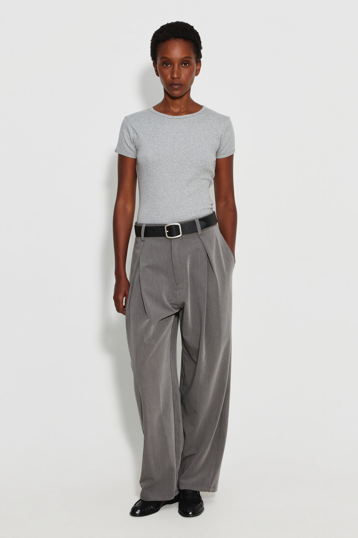 Maillot de corps femme gris chiné à manches courtes en coton Pima côtelé, porté avec un pantalon gris et une ceinture noire, vue de face en pied.