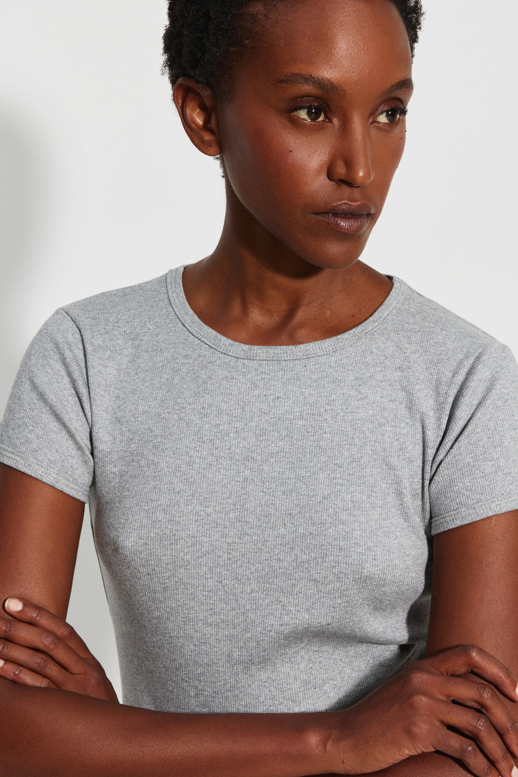 Maillot de corps femme gris chiné à manches courtes en coton Pima côtelé, vue rapprochée du col rond et de la maille, les bras croisés.