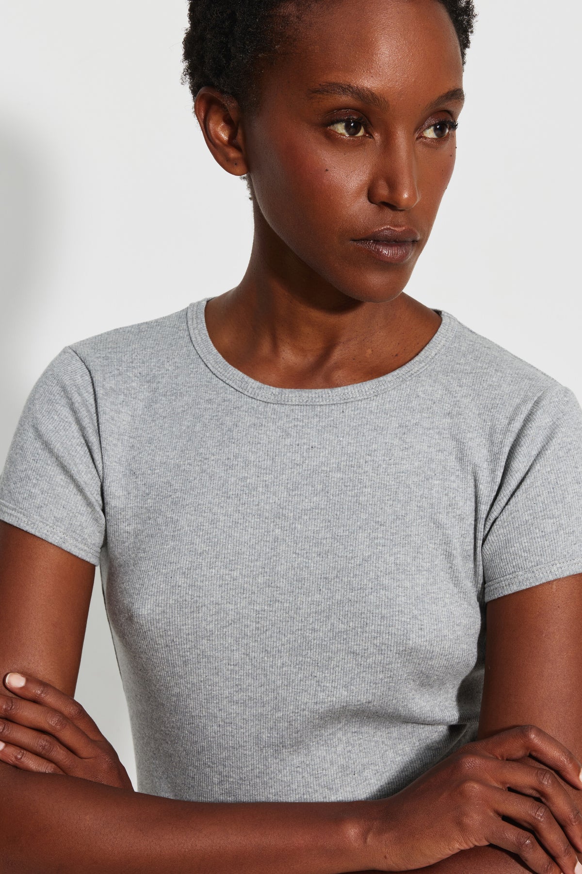 Maillot de corps femme gris chiné à manches courtes en coton Pima côtelé, vue rapprochée du col rond et de la maille, les bras croisés.
