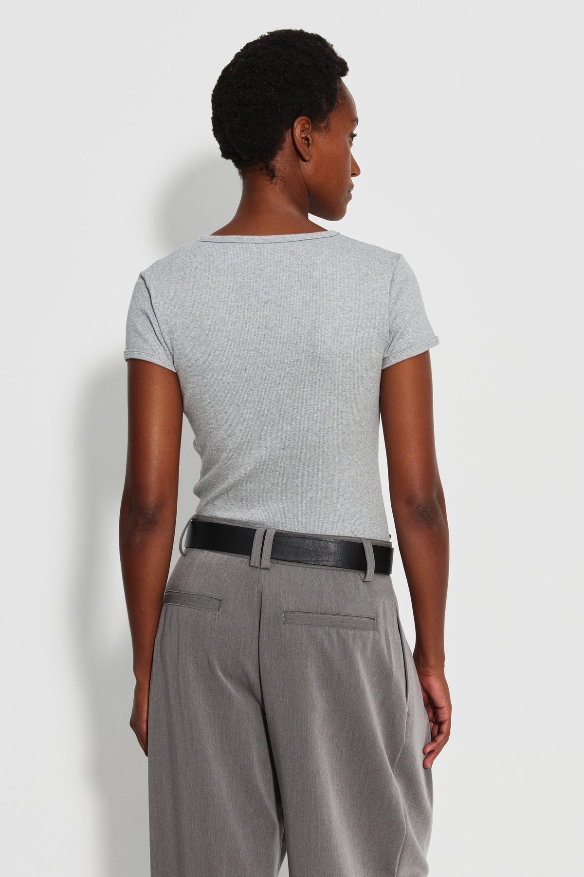 Maillot de corps femme gris chiné à manches courtes en coton Pima côtelé, porté de dos avec un pantalon gris et une ceinture noire.