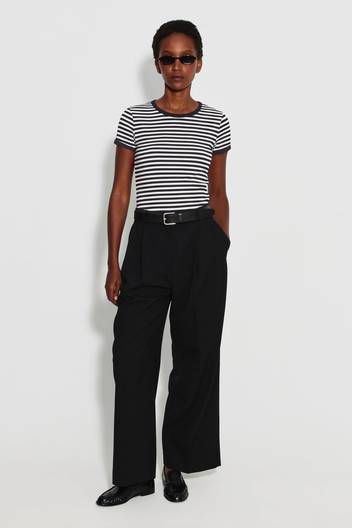 Maillot de corps femme noir et écru en coton bio côtelé à manches courtes, porté avec un pantalon noir, vue de face en pied.