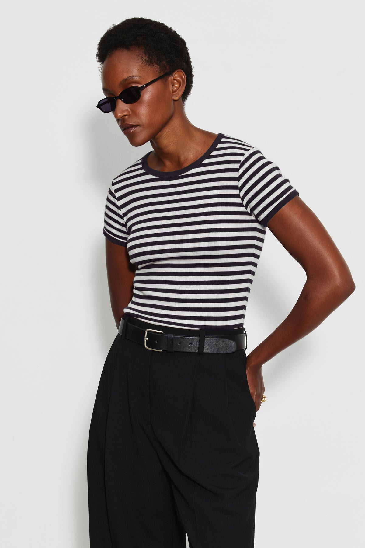 Maillot de corps femme noir et écru en coton bio côtelé à manches courtes, porté avec un pantalon noir ceinturé, vue de trois quarts. Made in France.
