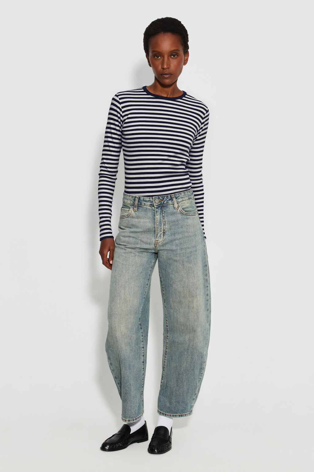 Maillot de corps femme bleu marine et écru en coton bio côtelé à manches longues, porté avec un jean bleu clair, vue en pied.