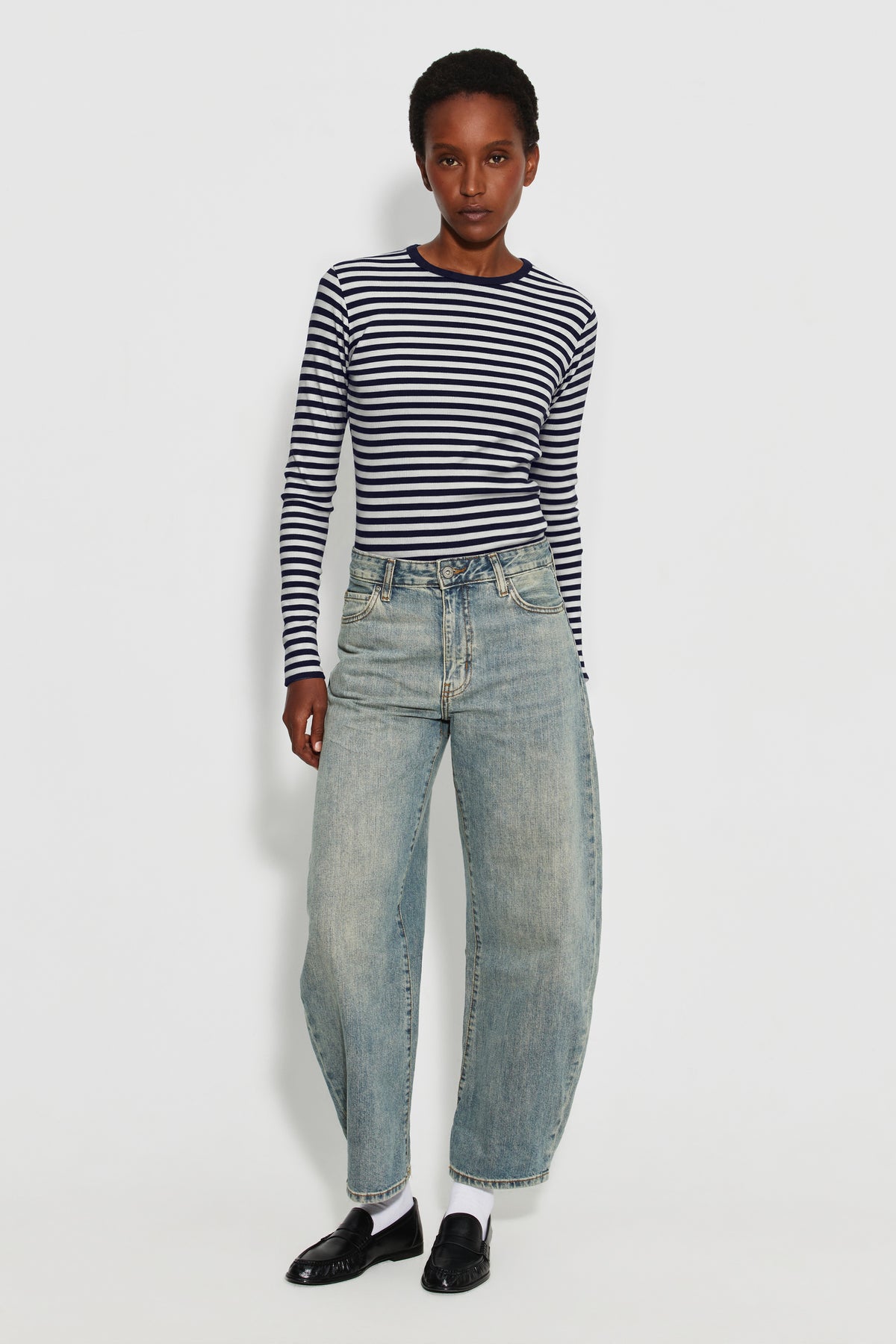 Maillot de corps femme bleu marine et écru en coton bio côtelé à manches longues, porté avec un jean bleu clair, vue en pied.