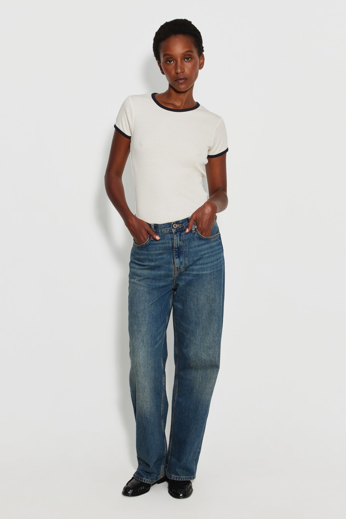 Maillot de corps femme bicolore écru et noir à manches courtes en coton Pima côtelé, porté avec un jean bleu et des chaussures noires, vue de face en pied.