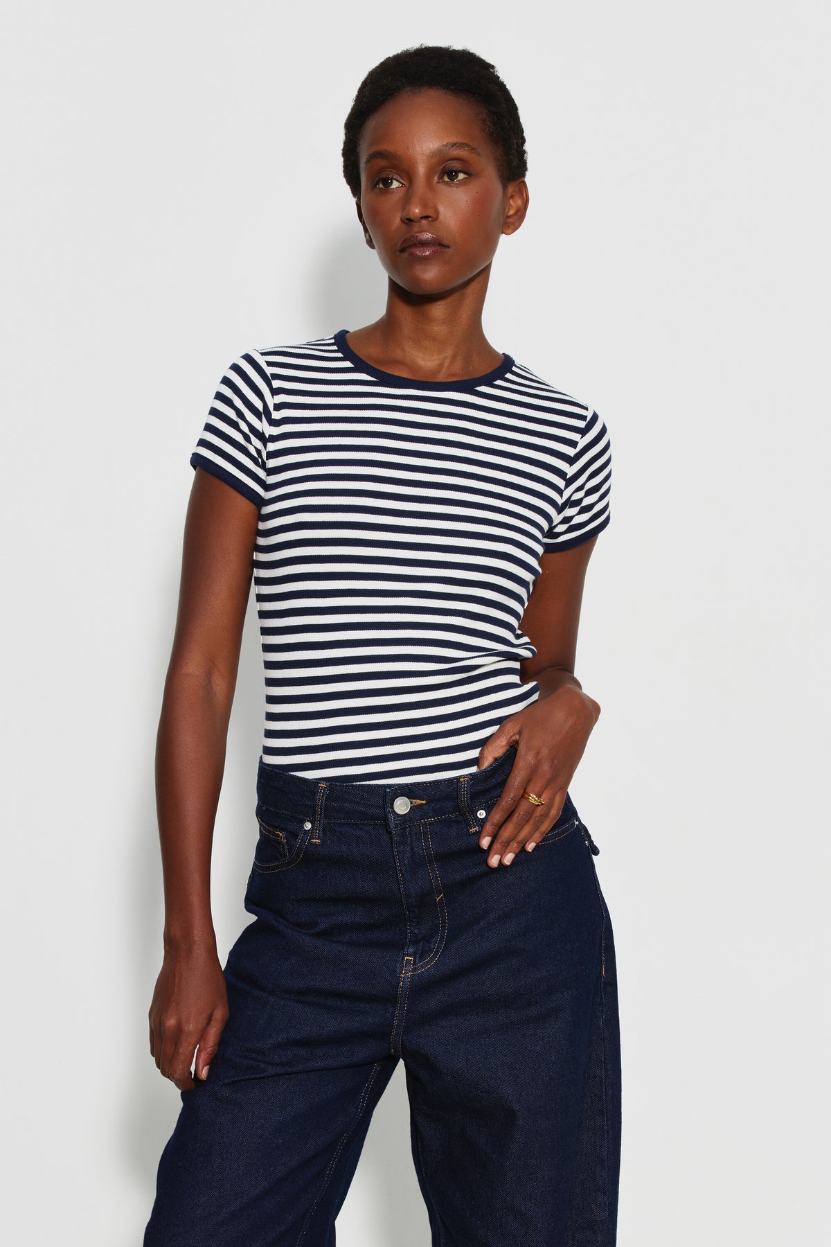 Maillot de corps femme bleu marine et écru en coton bio côtelé à manches courtes, porté de face avec un jean bleu foncé, une main près de la taille. Made in France.