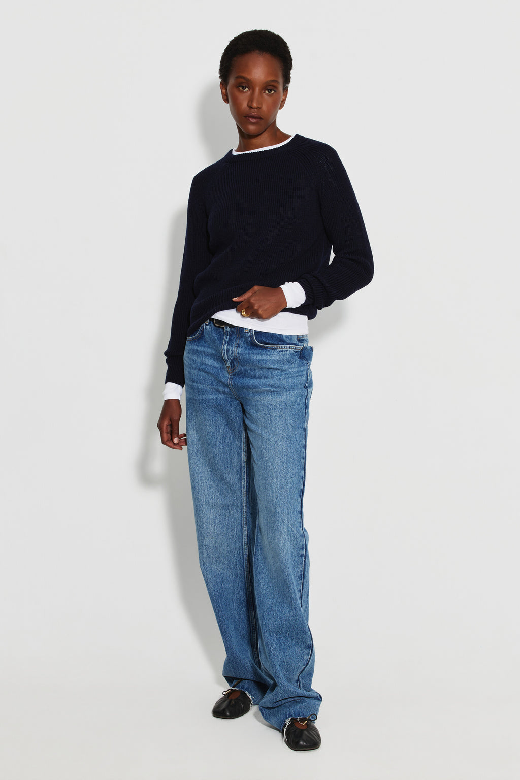 Pull femme bleu marine en laine mérinos à manches raglan, porté avec un jean bleu et un haut blanc visible au col et aux poignets, vue de face en pied.