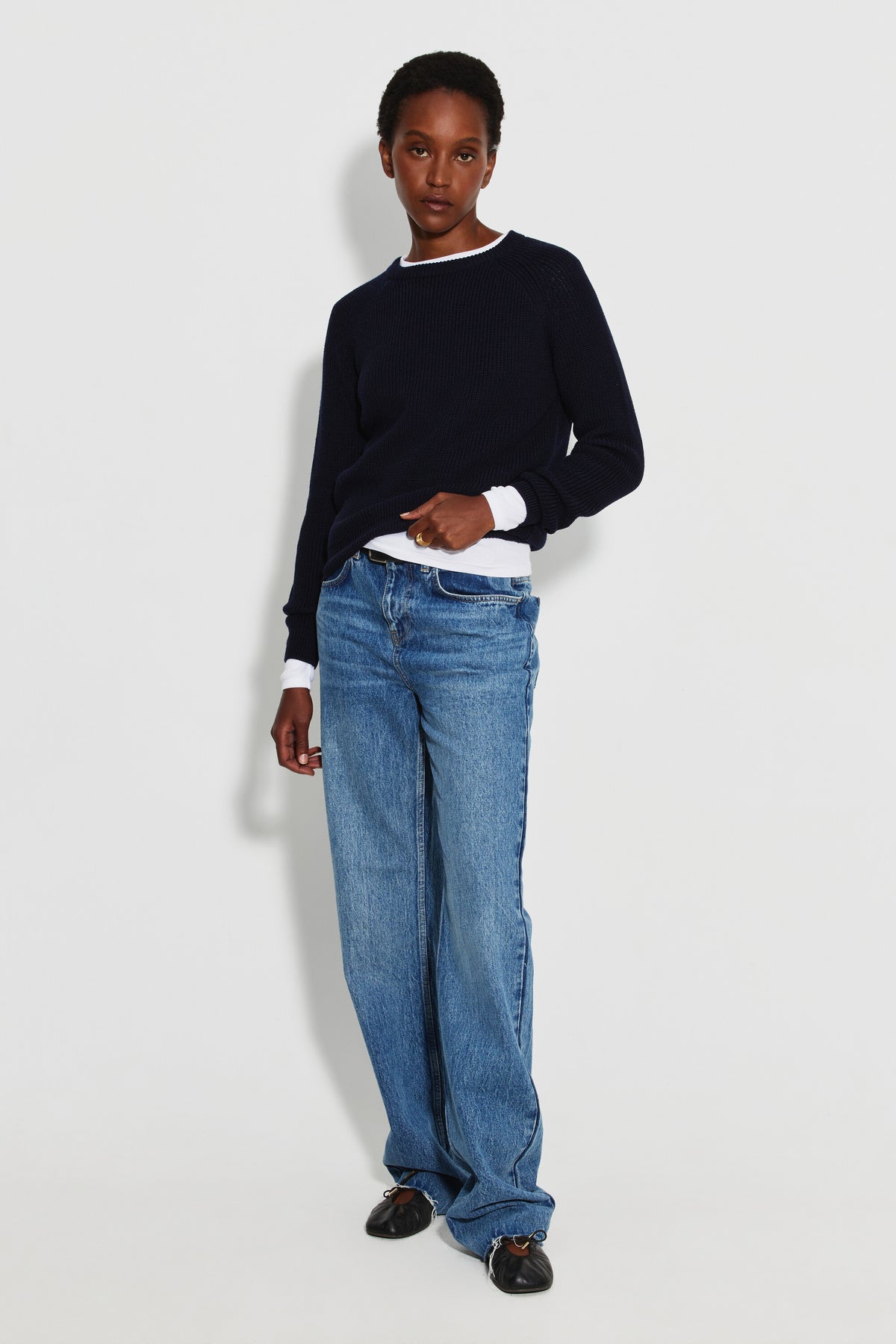 Pull femme bleu marine en laine mérinos à manches raglan, porté avec un jean bleu et un haut blanc visible au col et aux poignets, vue de face en pied.