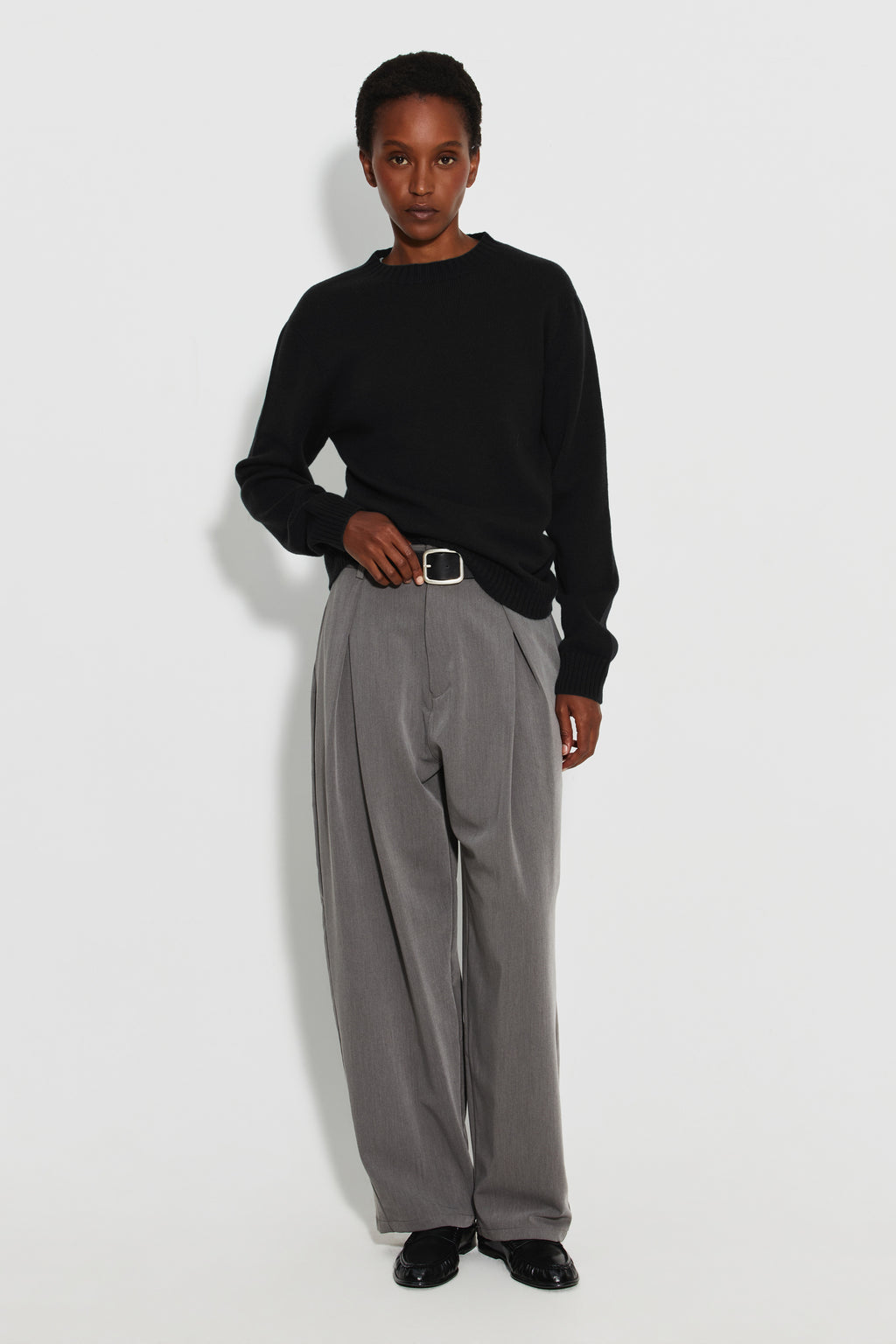 Pull femme noir en laine mérinos et cachemire, vue de face en pied avec un pantalon gris.