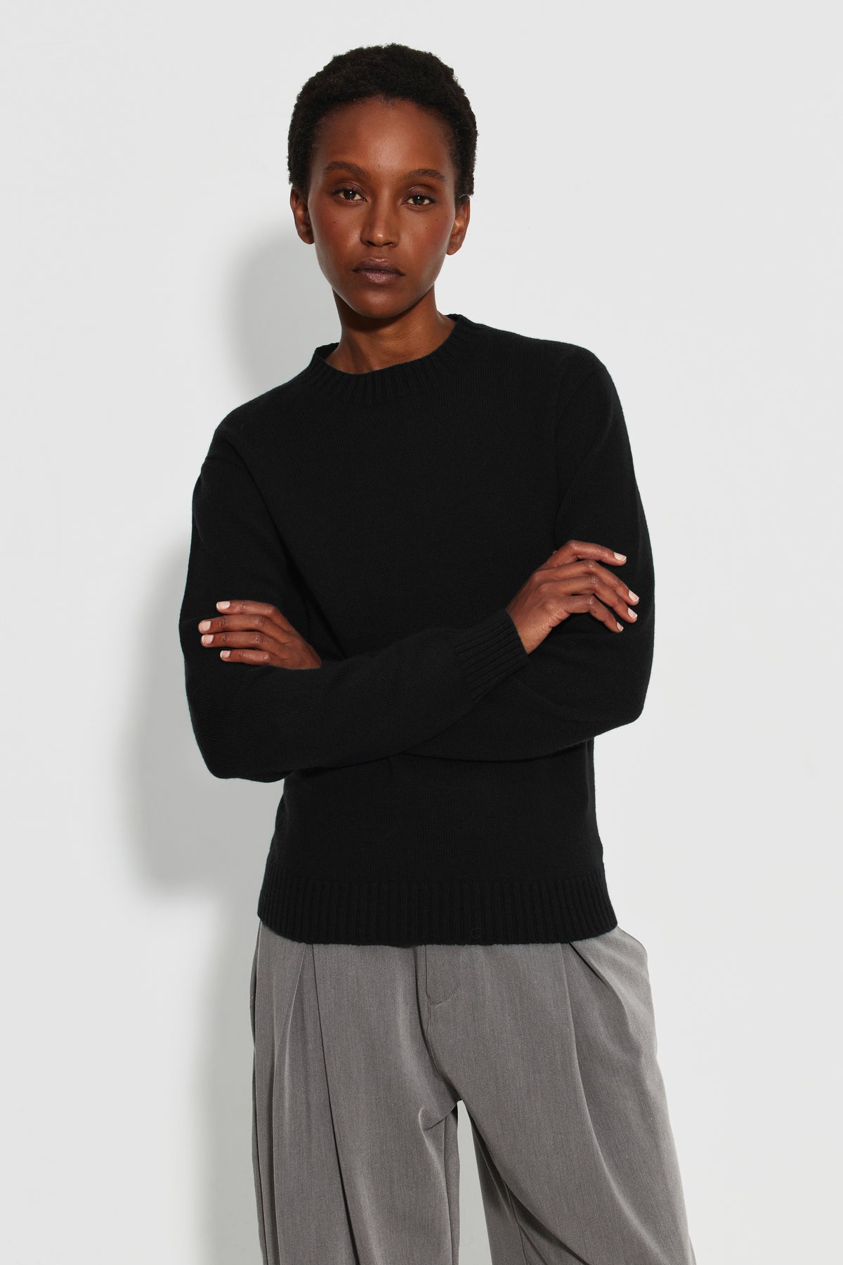 Pull femme noir en laine mérinos et cachemire, vue de face, bras croisés.