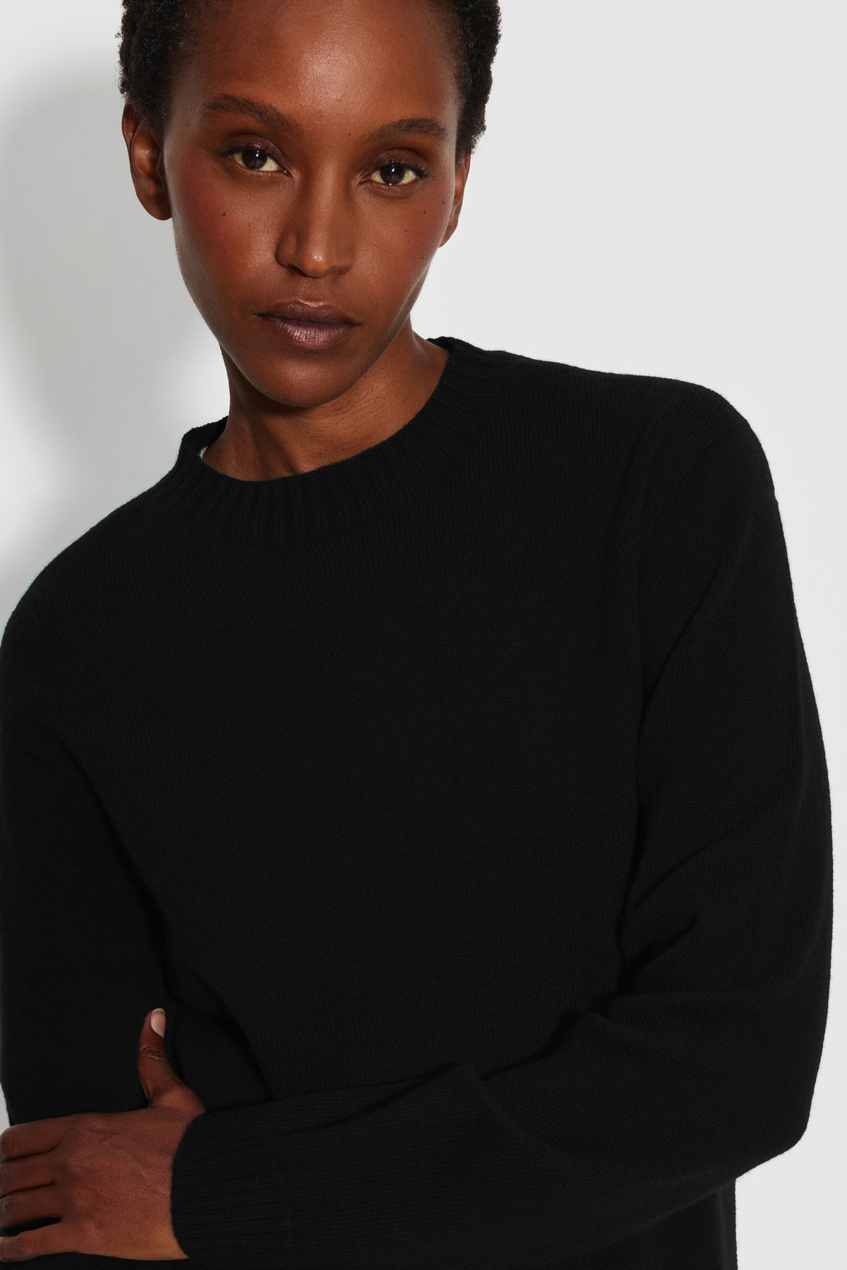 Pull femme noir en laine mérinos et cachemire, détail du col rond et de la maille.