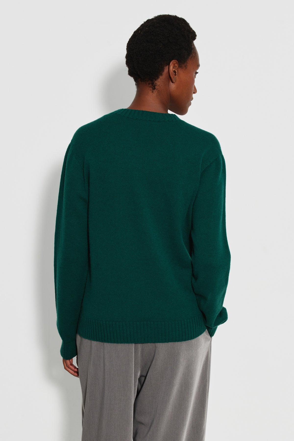Pull mérinos et cachemire femme vert – vue de dos avec un pantalon gris.