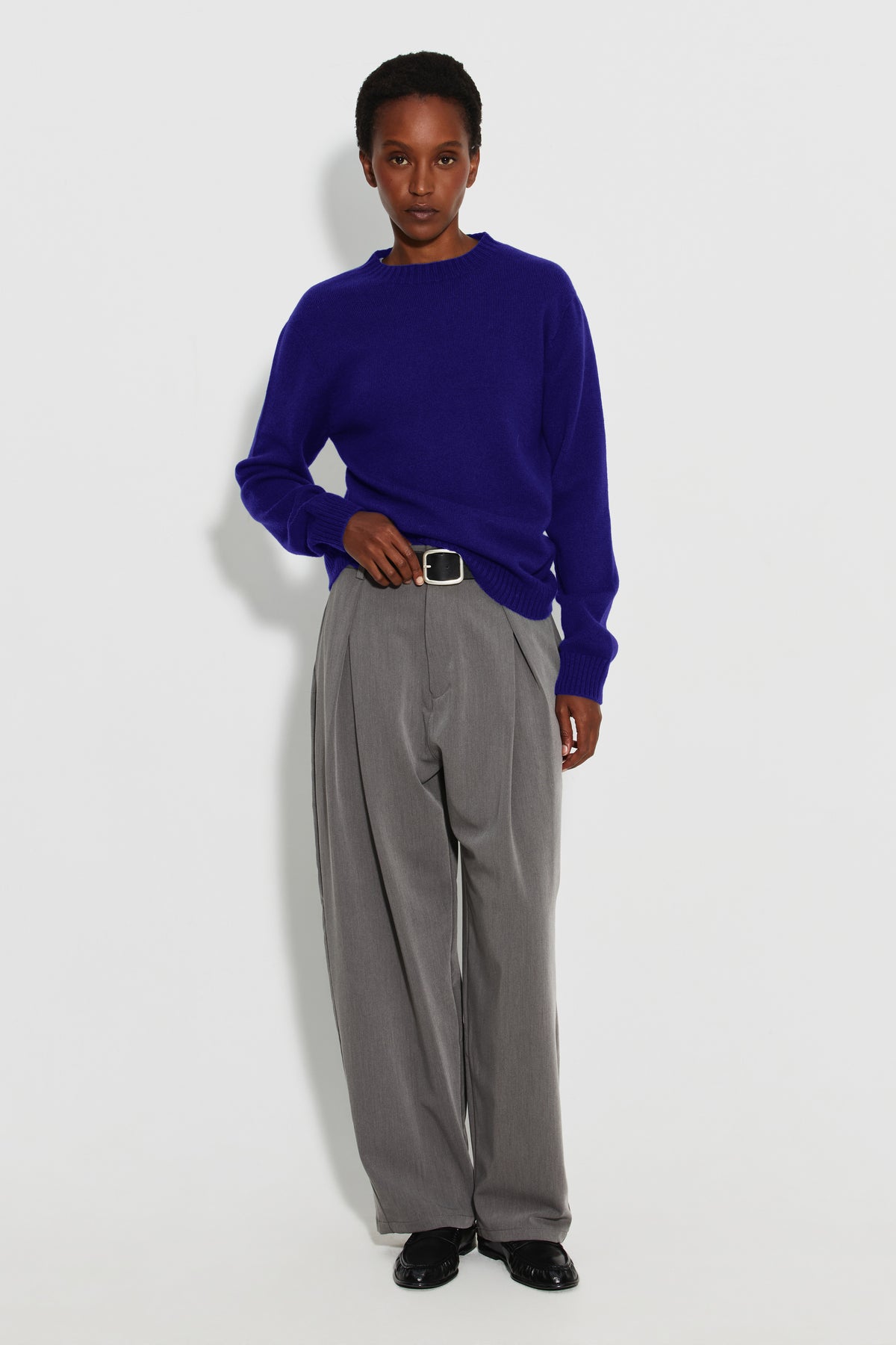 Pull femme violet en laine mérinos et cachemire, vue de face en pied avec un pantalon gris.