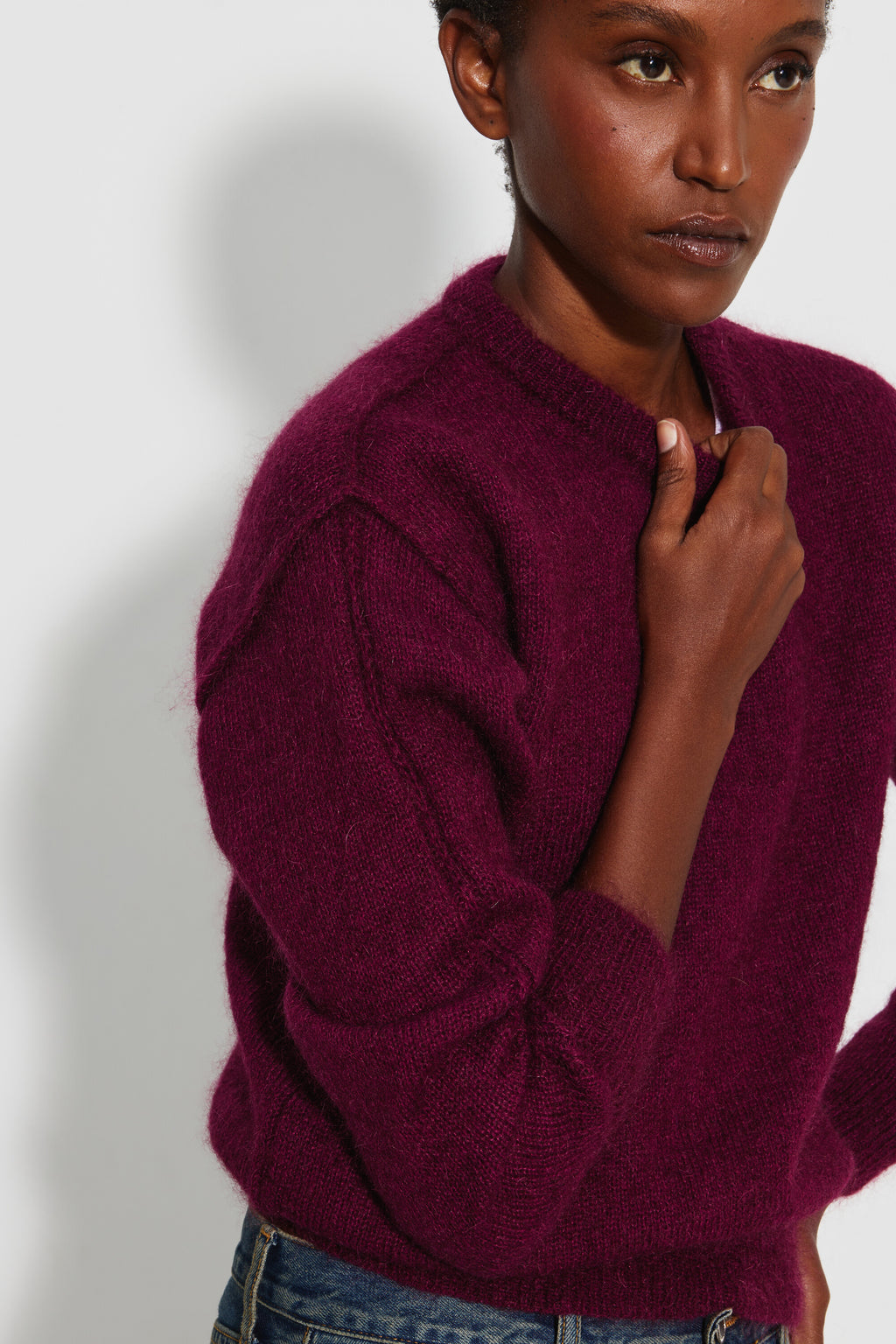Pull mohair à manches longues femme bordeaux – portrait de trois quarts, une main près du col rond.