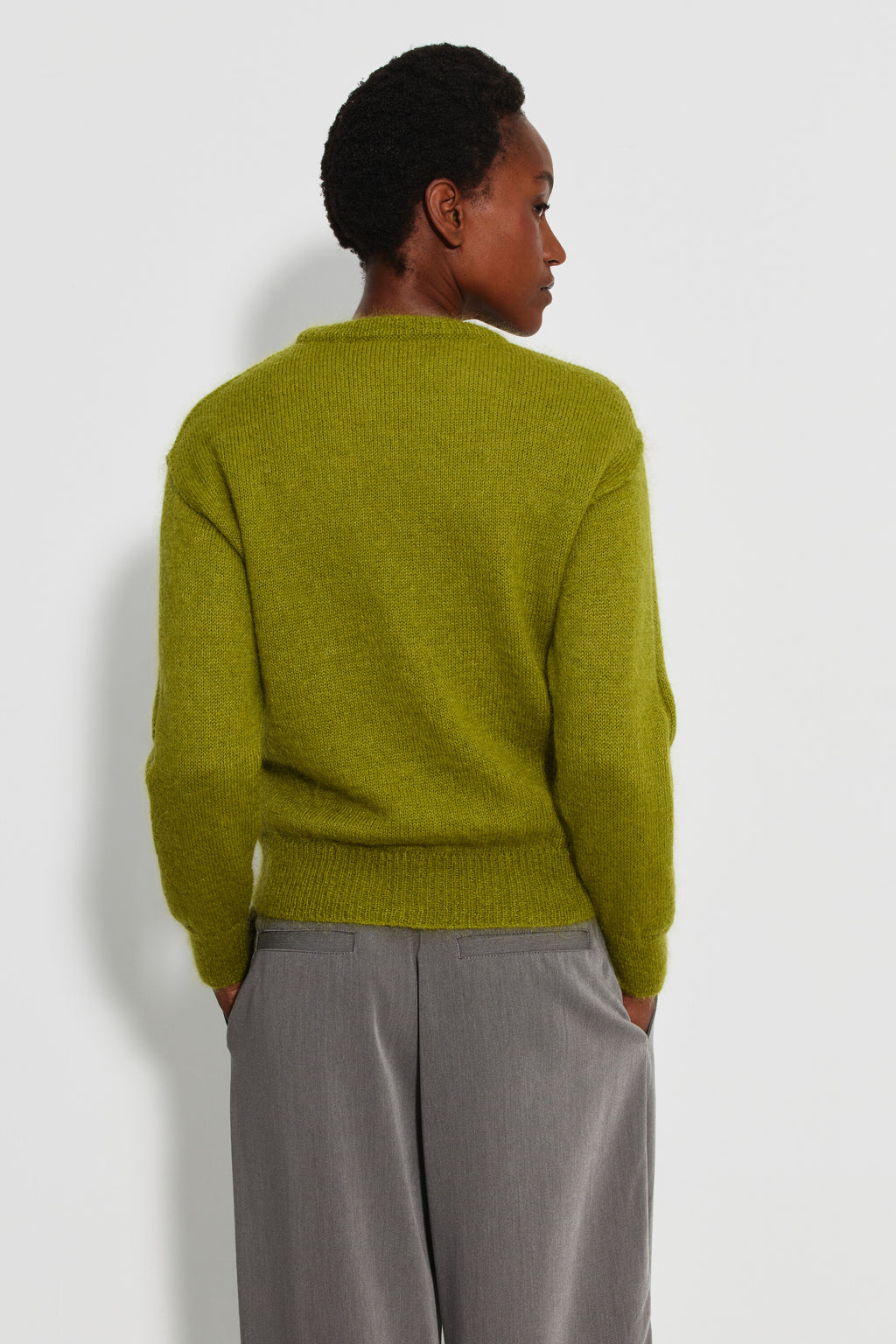 Pull mohair à manches longues femme vert mousse – vue de dos avec un pantalon gris.