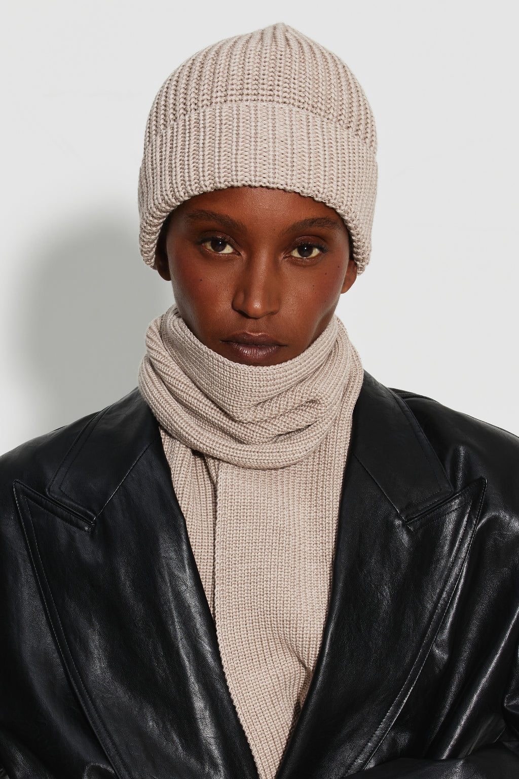 Bonnet femme beige en laine mérinos, portrait de face montrant le revers et la maille côtelée, avec une écharpe assortie. Made in France.