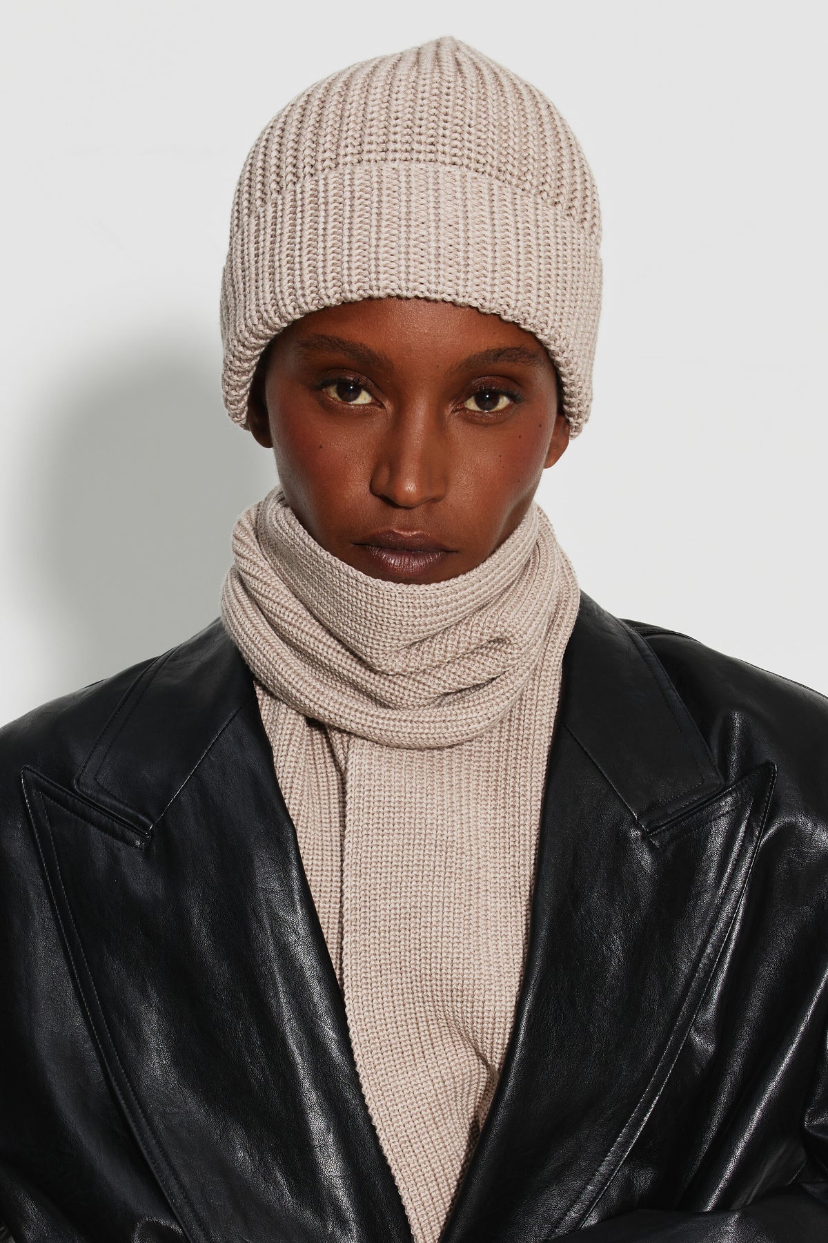 Bonnet femme beige en laine mérinos, portrait de face montrant le revers et la maille côtelée, avec une écharpe assortie. Made in France.