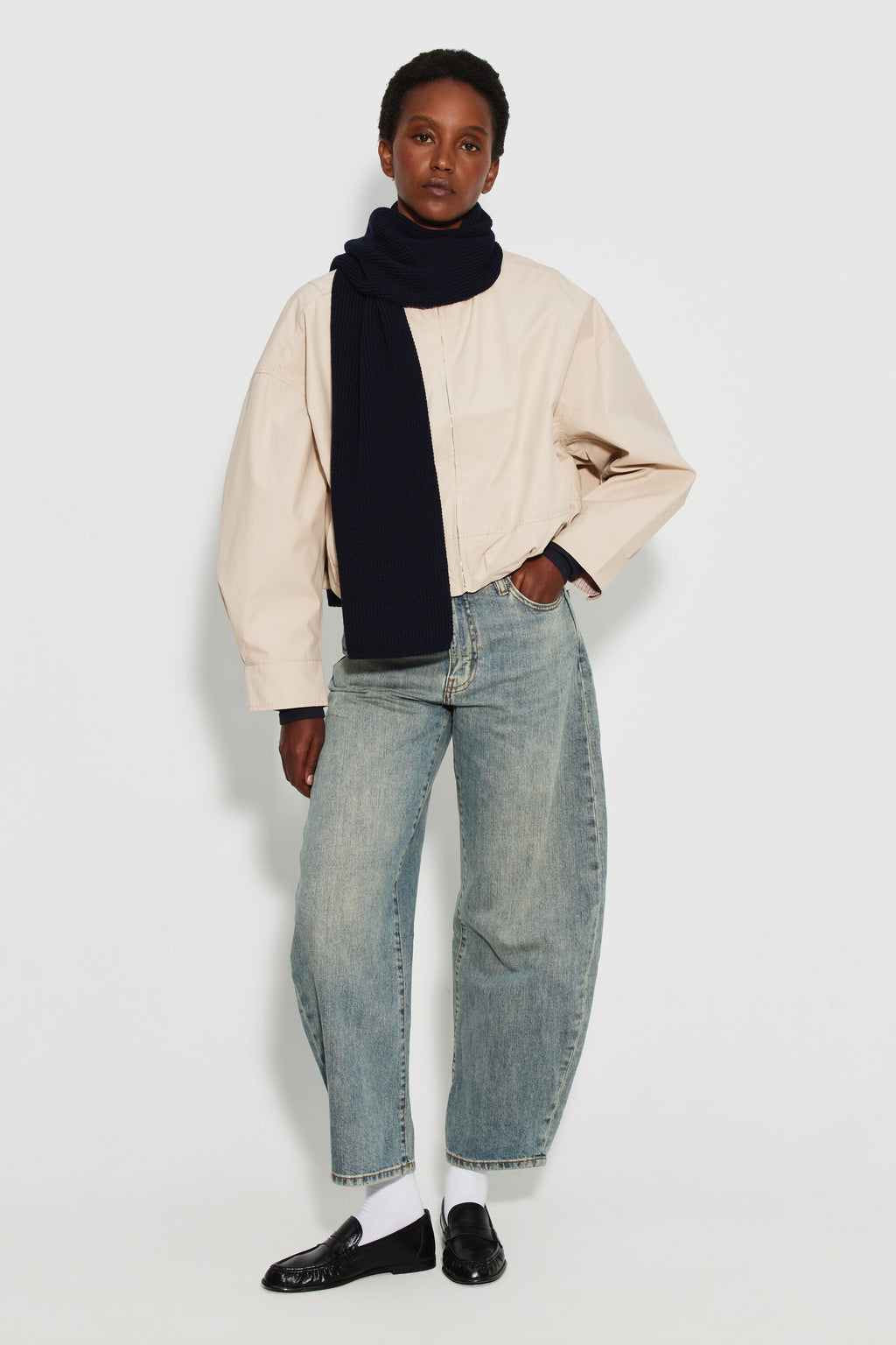 Écharpe femme bleu marine en laine mérinos, portée autour du cou avec une veste claire et un jean clair, vue de face en pied.