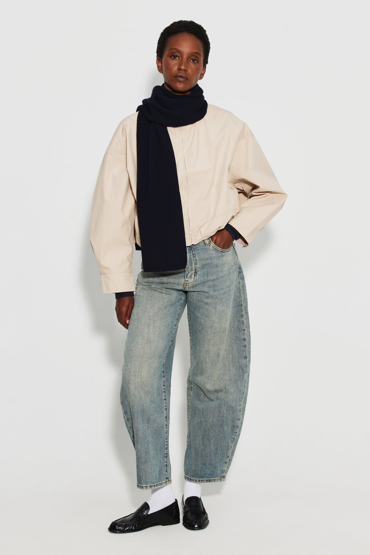 Écharpe femme bleu marine en laine mérinos, portée autour du cou avec une veste claire et un jean clair, vue de face en pied.