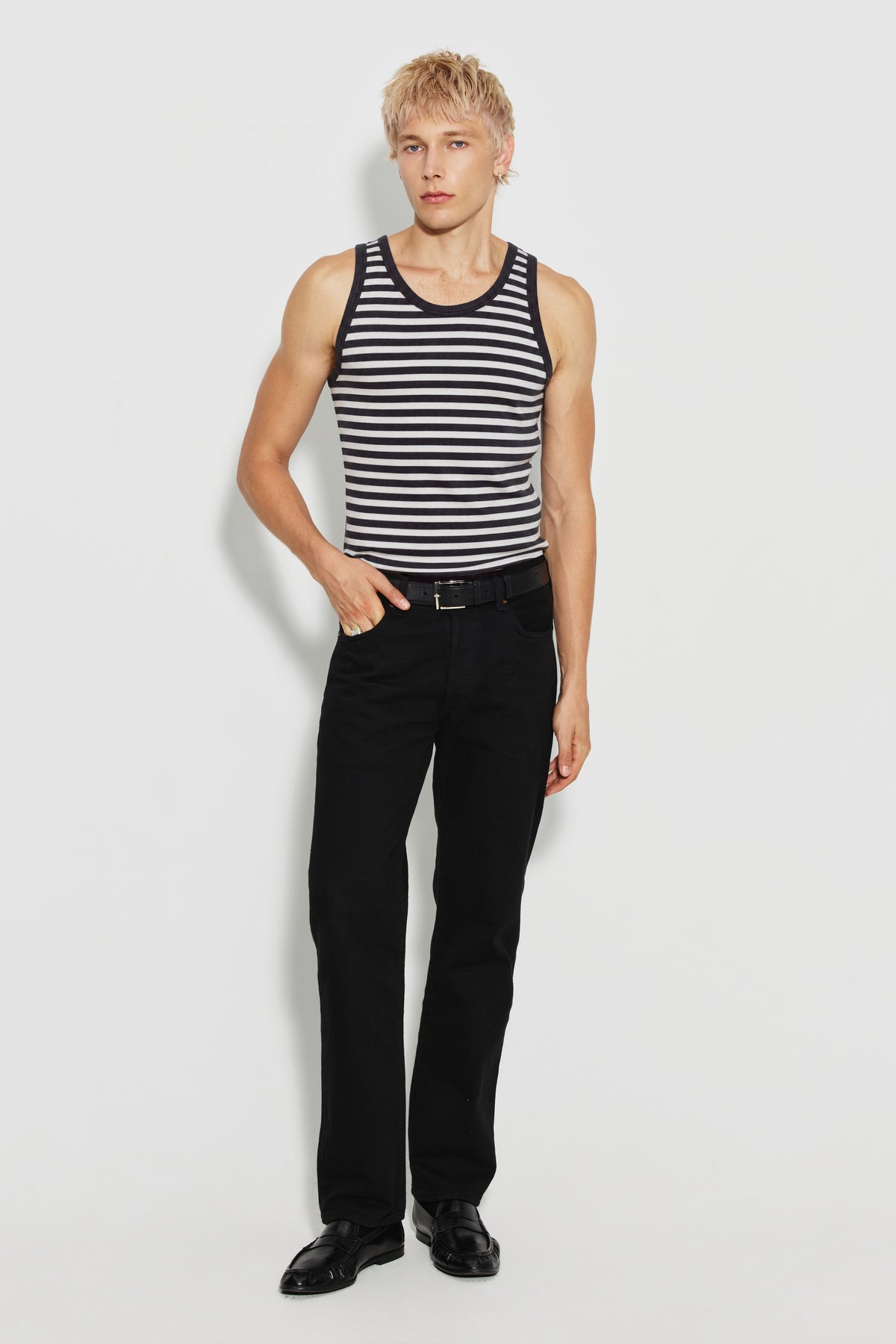 Débardeur homme rayé noir et écru en coton bio côtelé, porté avec un pantalon noir, les mains dans les poches, vue de face en pied.