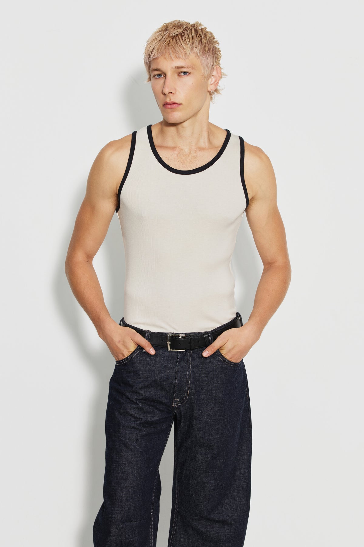 Débardeur homme écru et noir en coton Pima côtelé, porté de face avec un jean foncé, les mains dans les poches. Made in France.