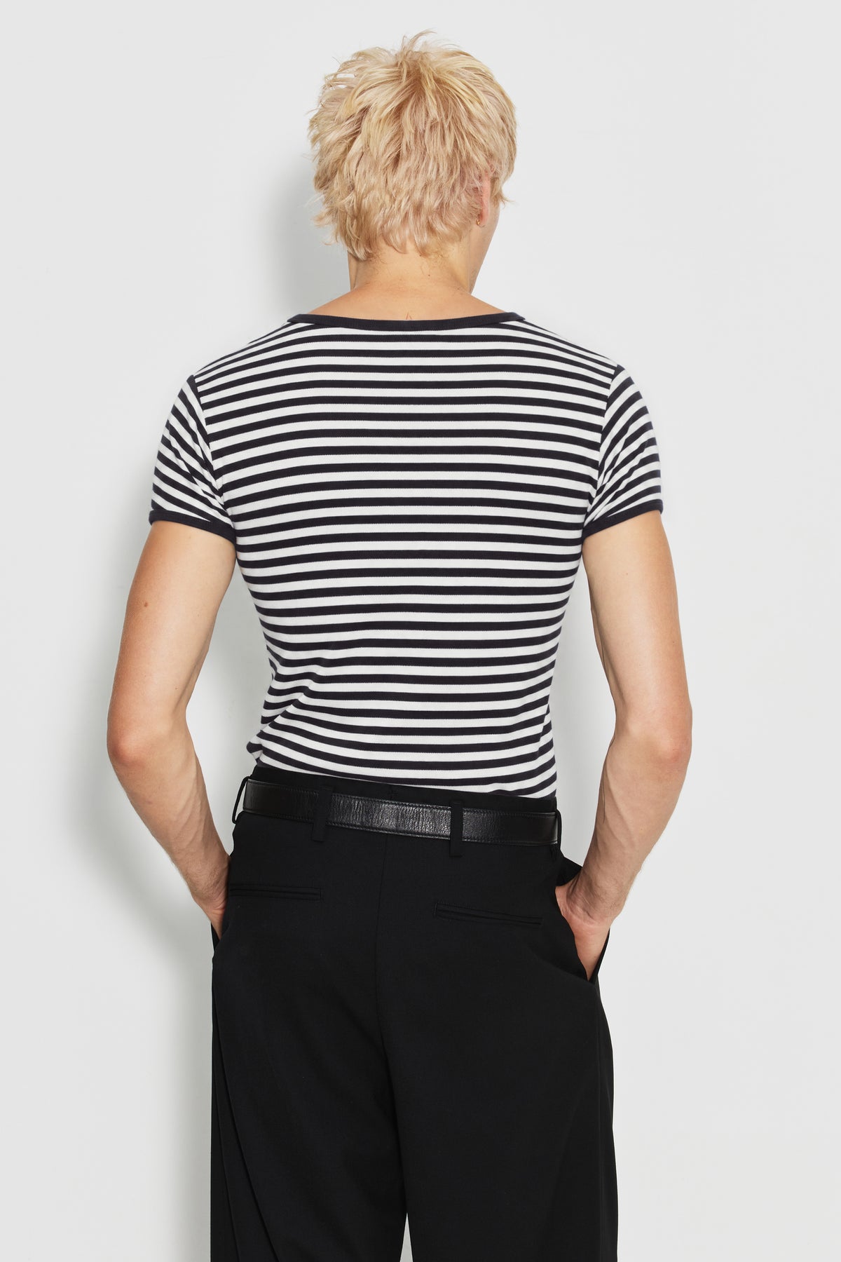 Maillot de corps homme noir et écru en coton bio côtelé à manches courtes, porté de dos avec un pantalon noir, vue des rayures et des manches.