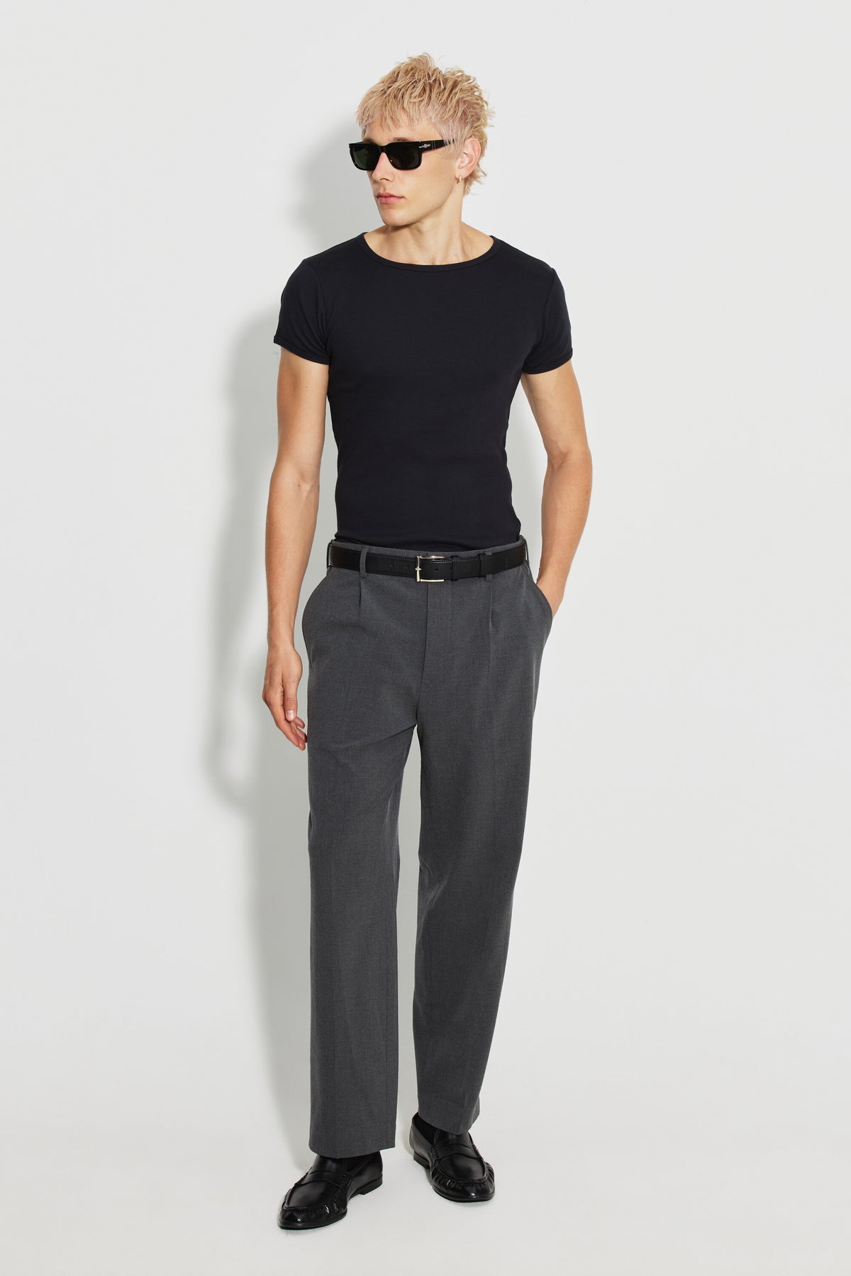 Maillot de corps homme noir à manches courtes en coton Pima côtelé, porté avec un pantalon gris et des lunettes de soleil, vue de face en pied.