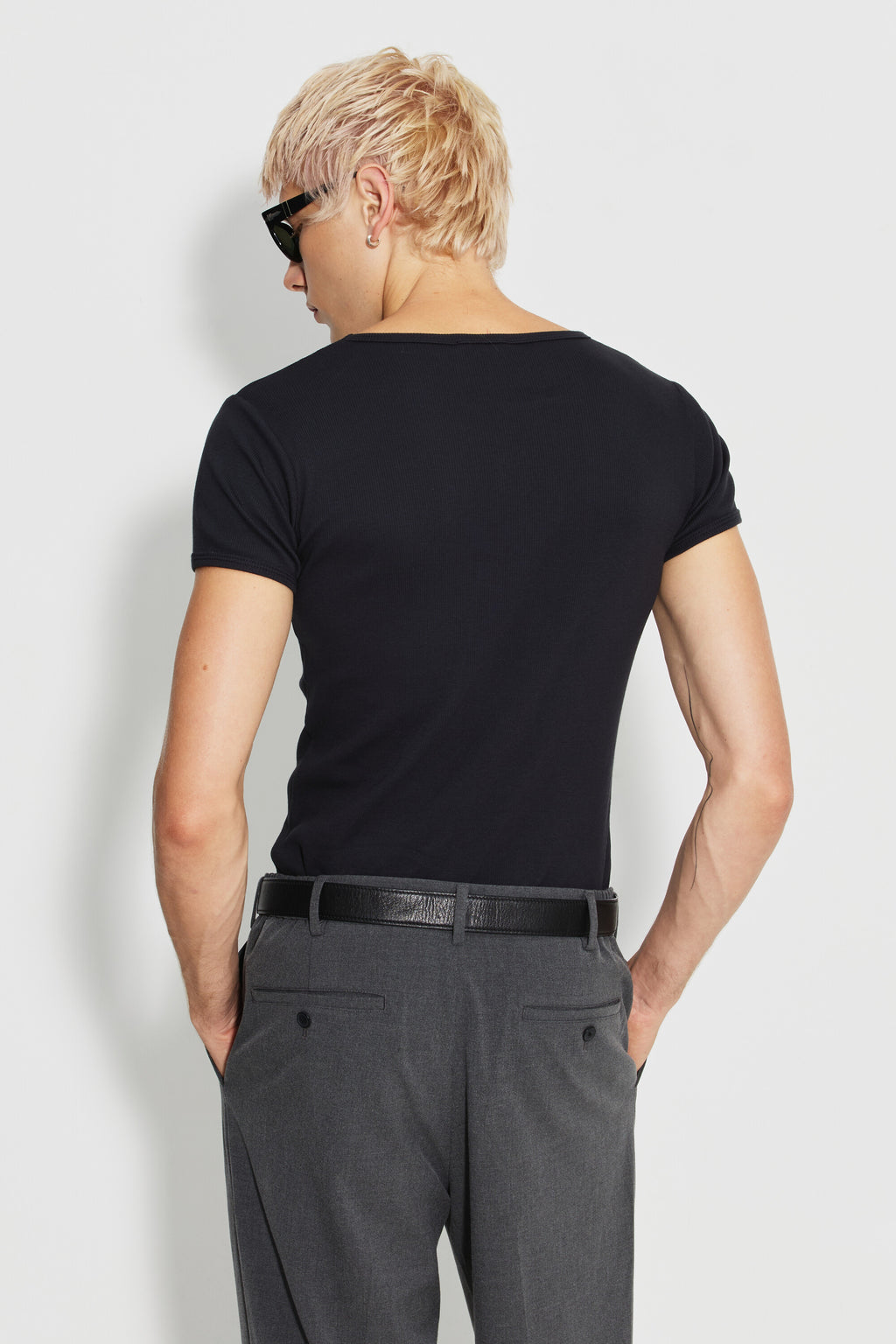 Maillot de corps homme noir à manches courtes en coton Pima côtelé, porté de dos avec un pantalon gris, la tête tournée sur le côté.